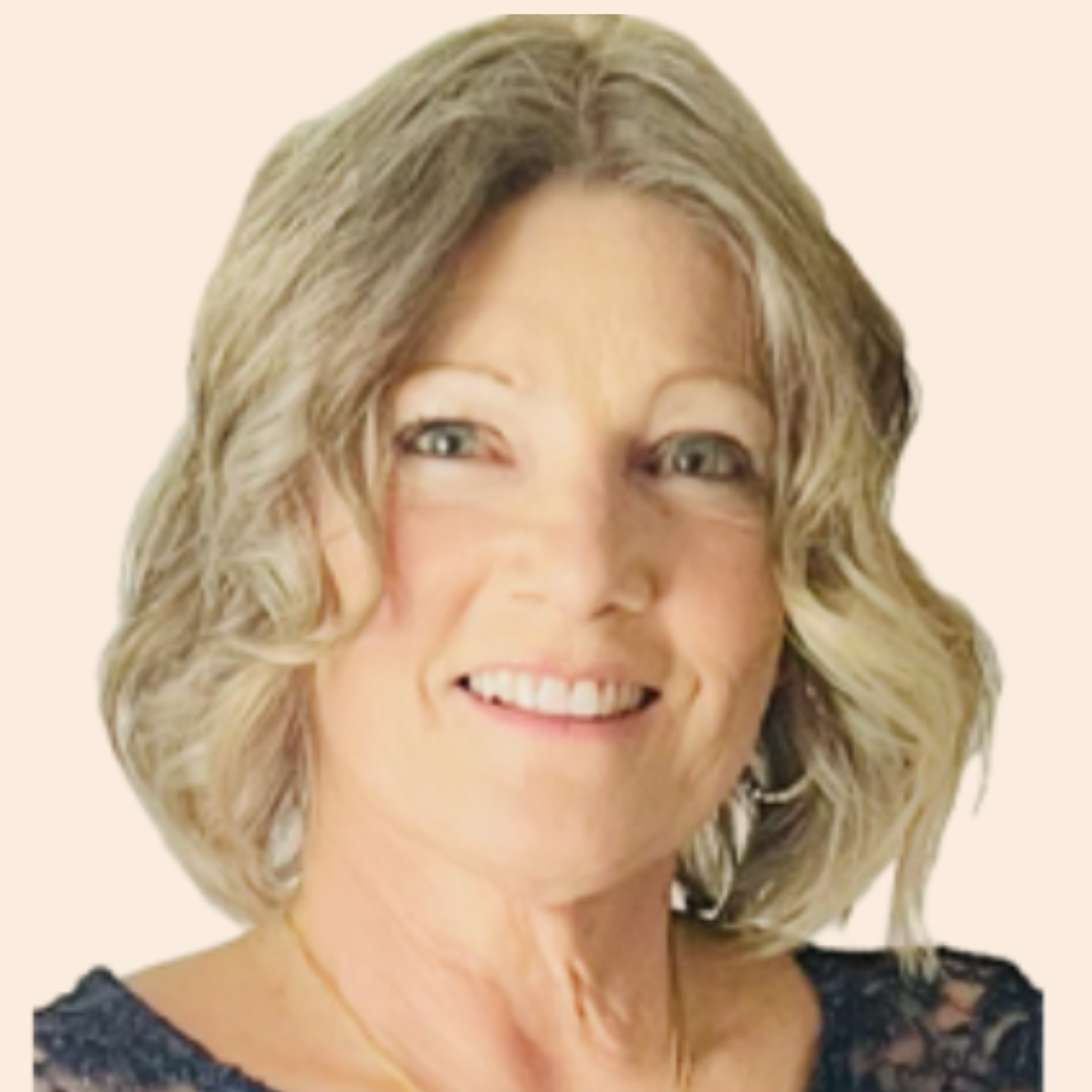 Smiling middle-aged woman with blonde, wavy hair and light complexion, wearing a dark lace top.