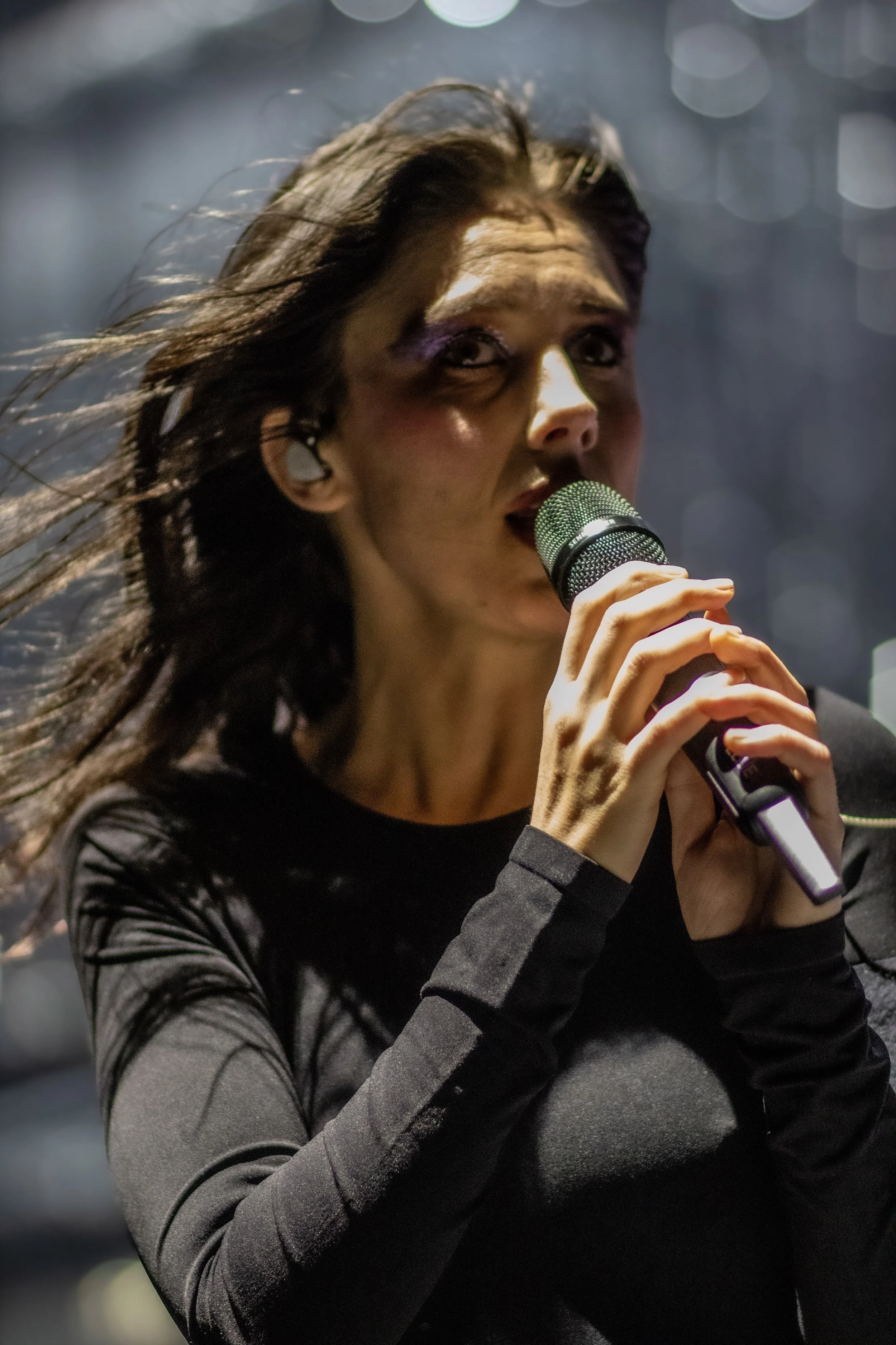 A female singer holding a microphone and singing on stage.