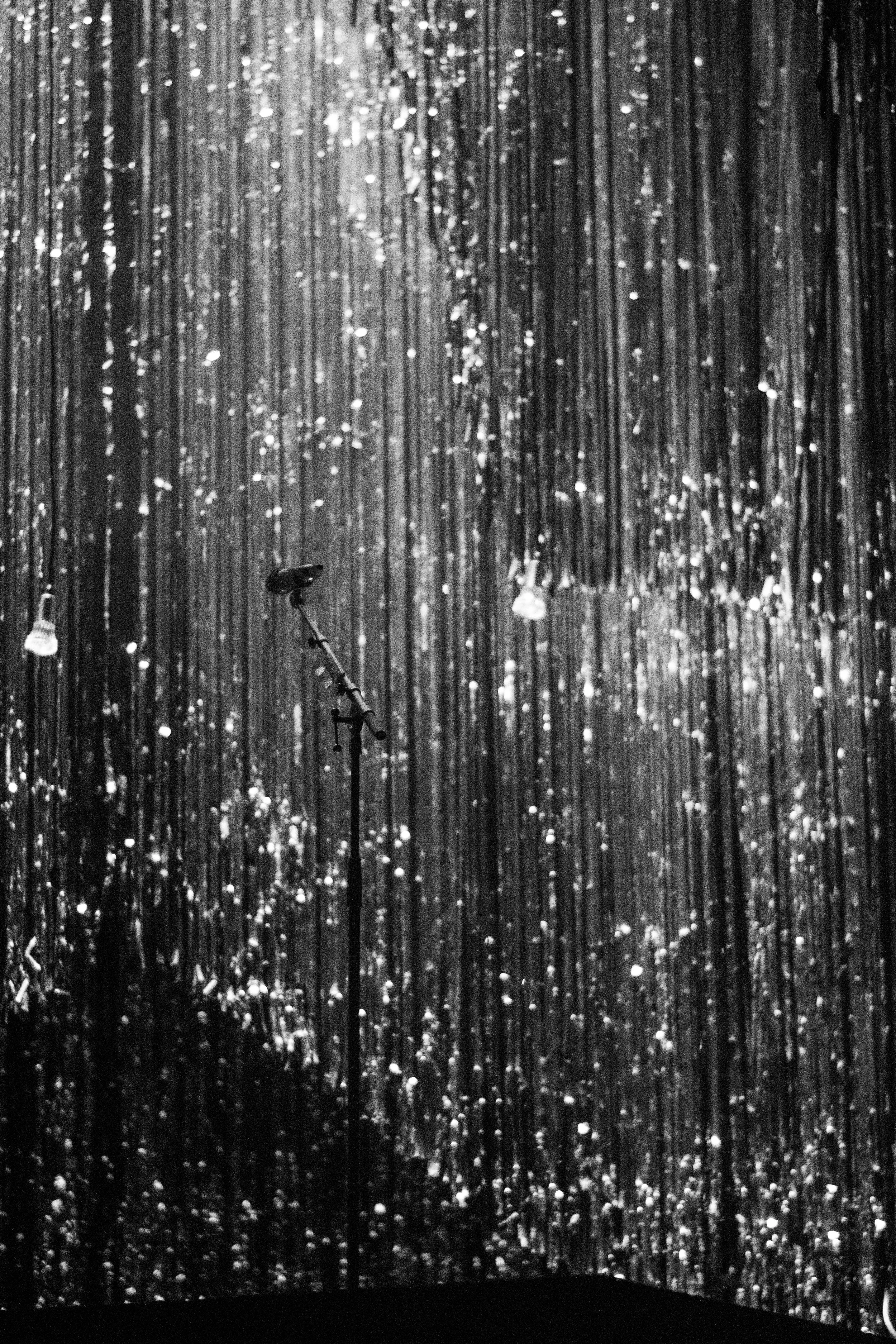 A microphone stand in front of a shimmering silver curtain.