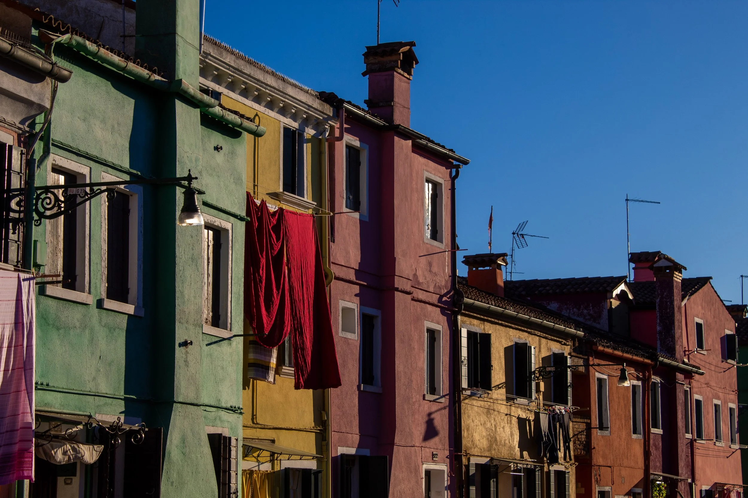 Colorful buildings with laundry hanging outside on a clear day in Venice, Italy.