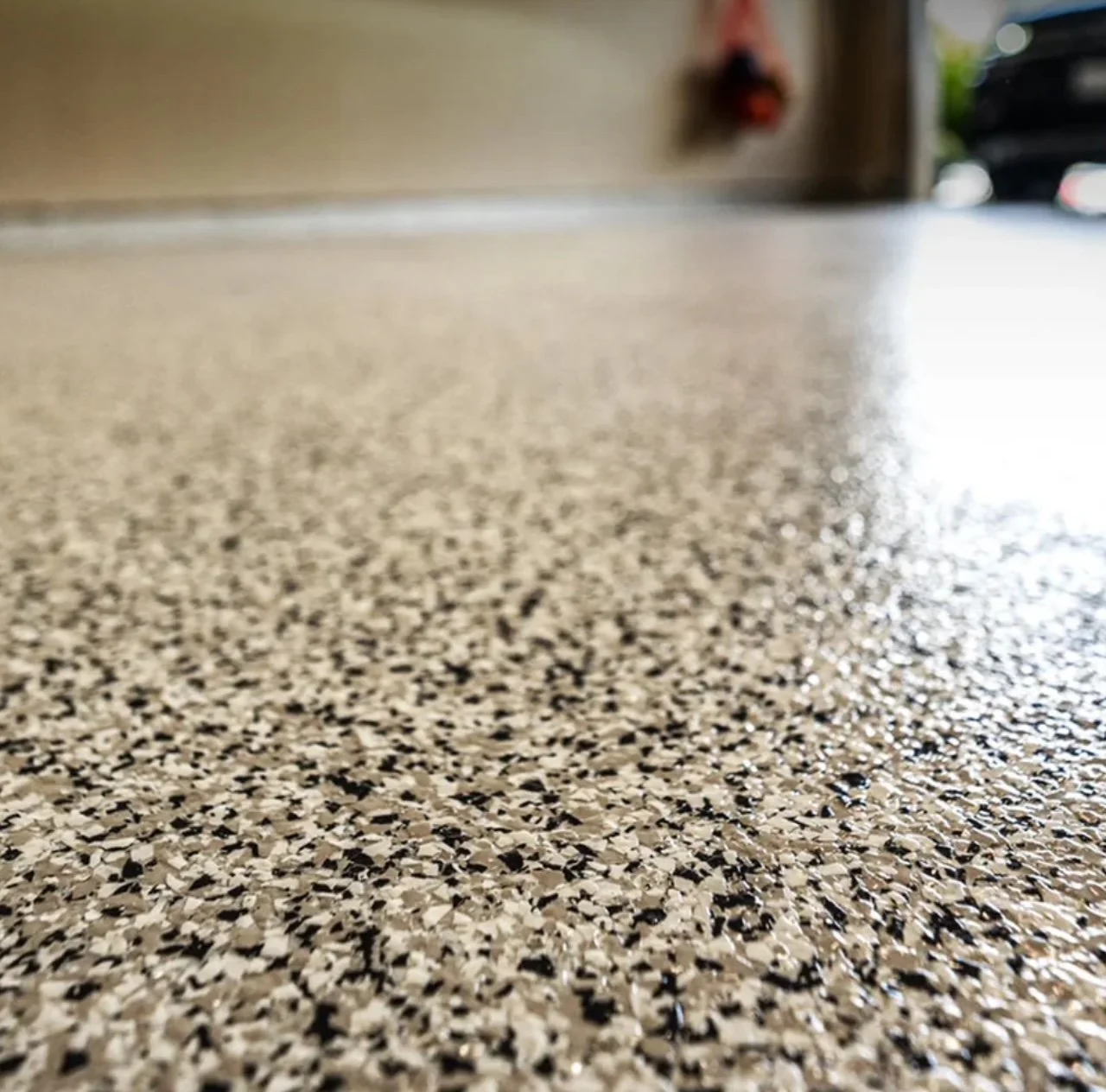 Close-up of a textured speckled beige and black countertop surface with a blurred background.