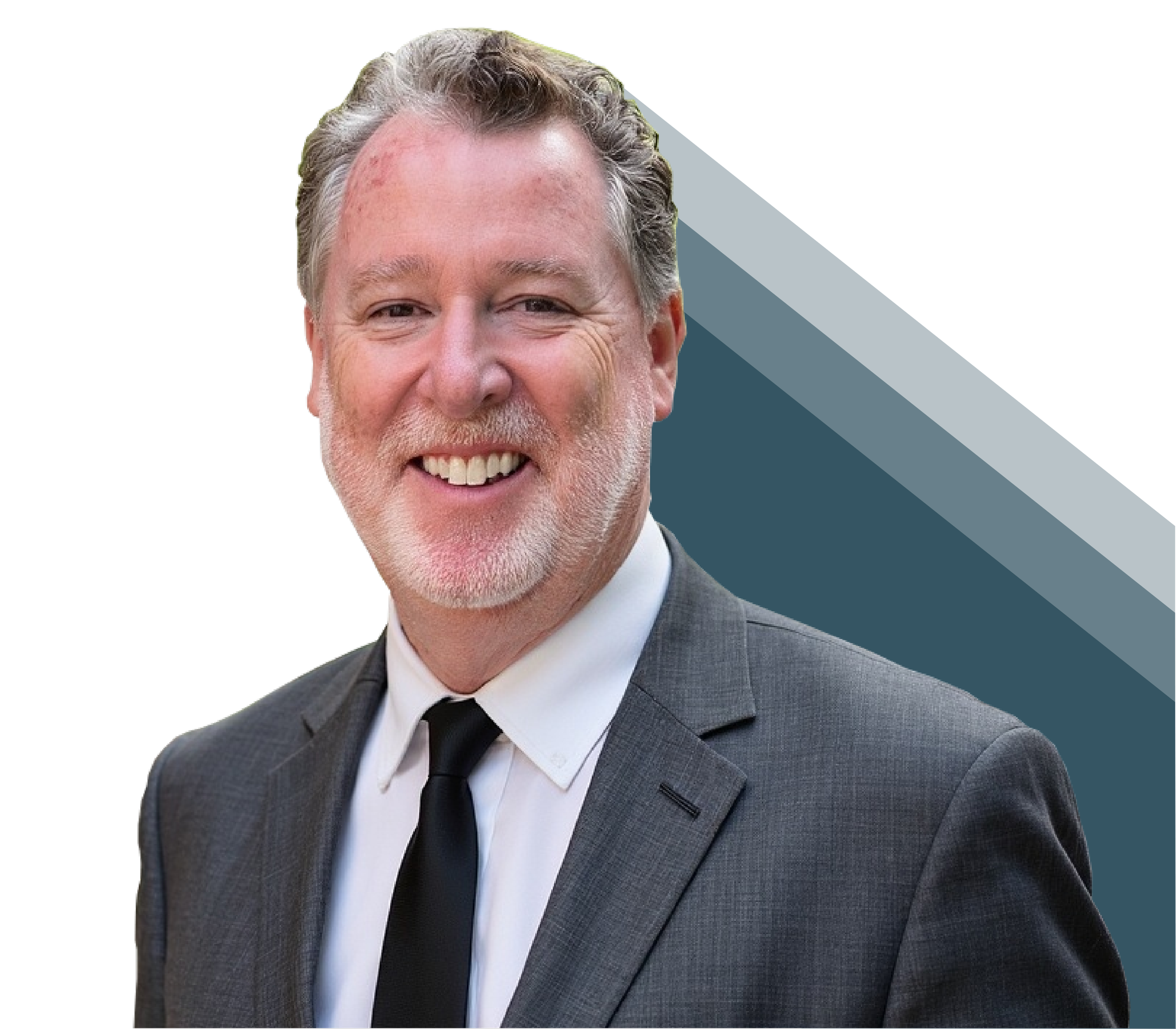 A smiling middle-aged man in a gray suit, white shirt, and black tie, with gray hair and a beard, against a background with a dark blue and black geometric design.