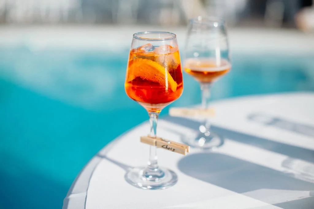 Deux verres de cocktail avec des agrumes sur une table près d'une piscine par une journée ensoleillée