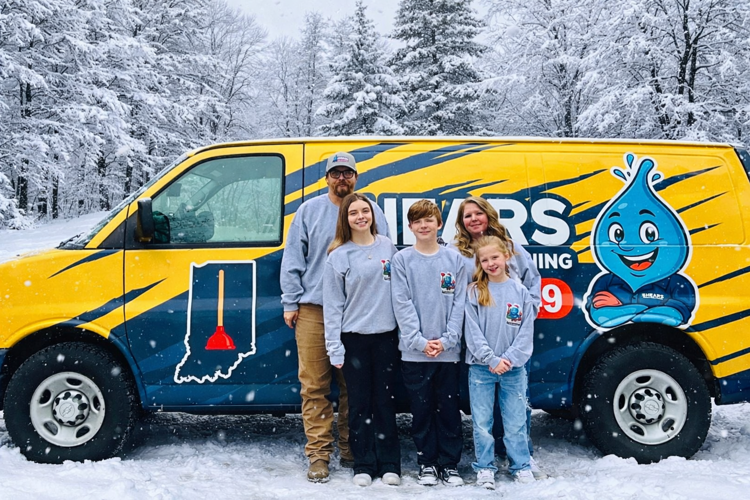 A family of five standing in front of a yellow and blue service van with graphics of a water droplet character and a plunger on the side, in a snowy outdoor setting with snow-covered trees in the background.