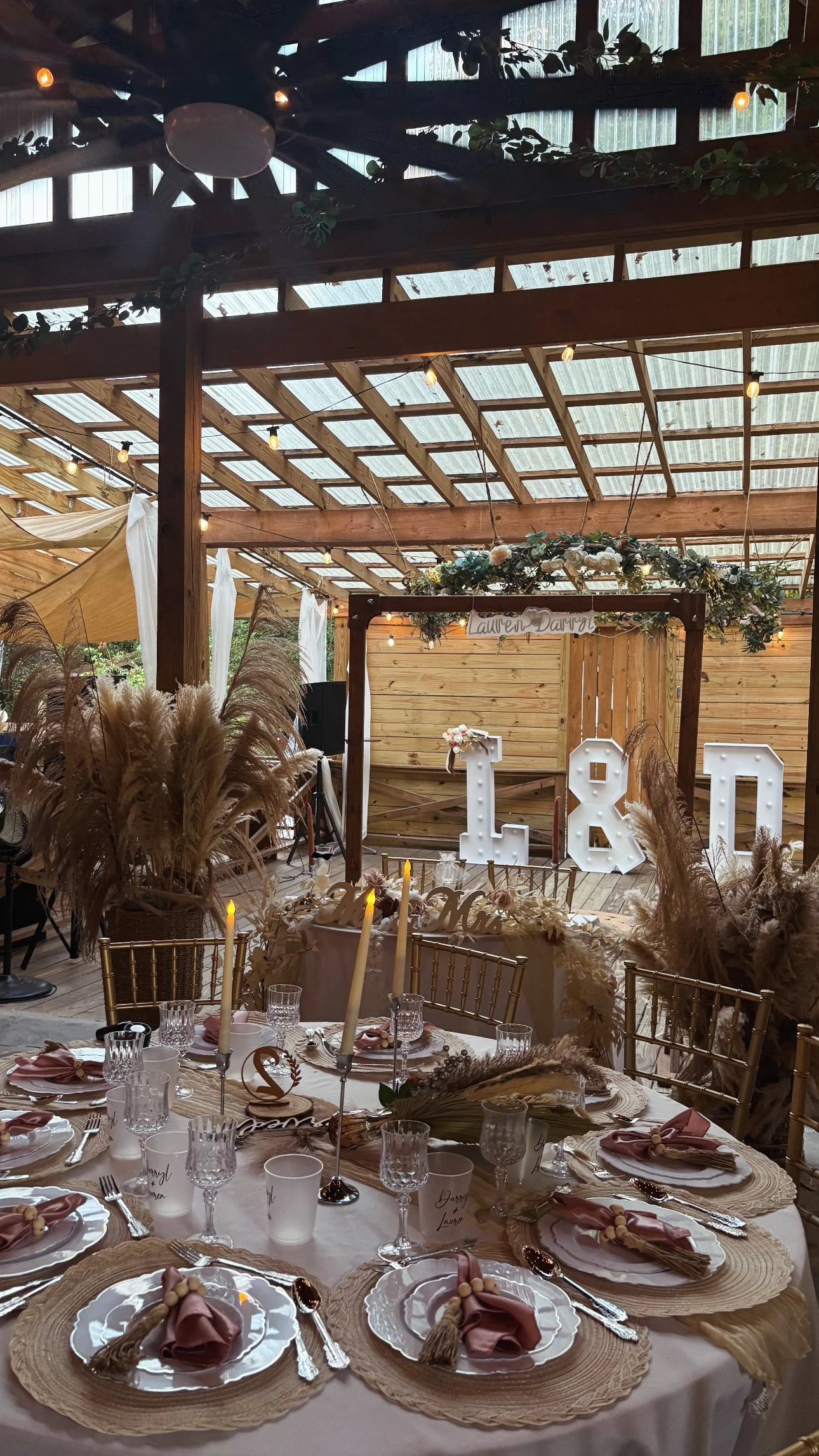 Indoor wedding reception table setting with elegant decor, feather arrangements, candles, and large illuminated numbers 18 in the background.