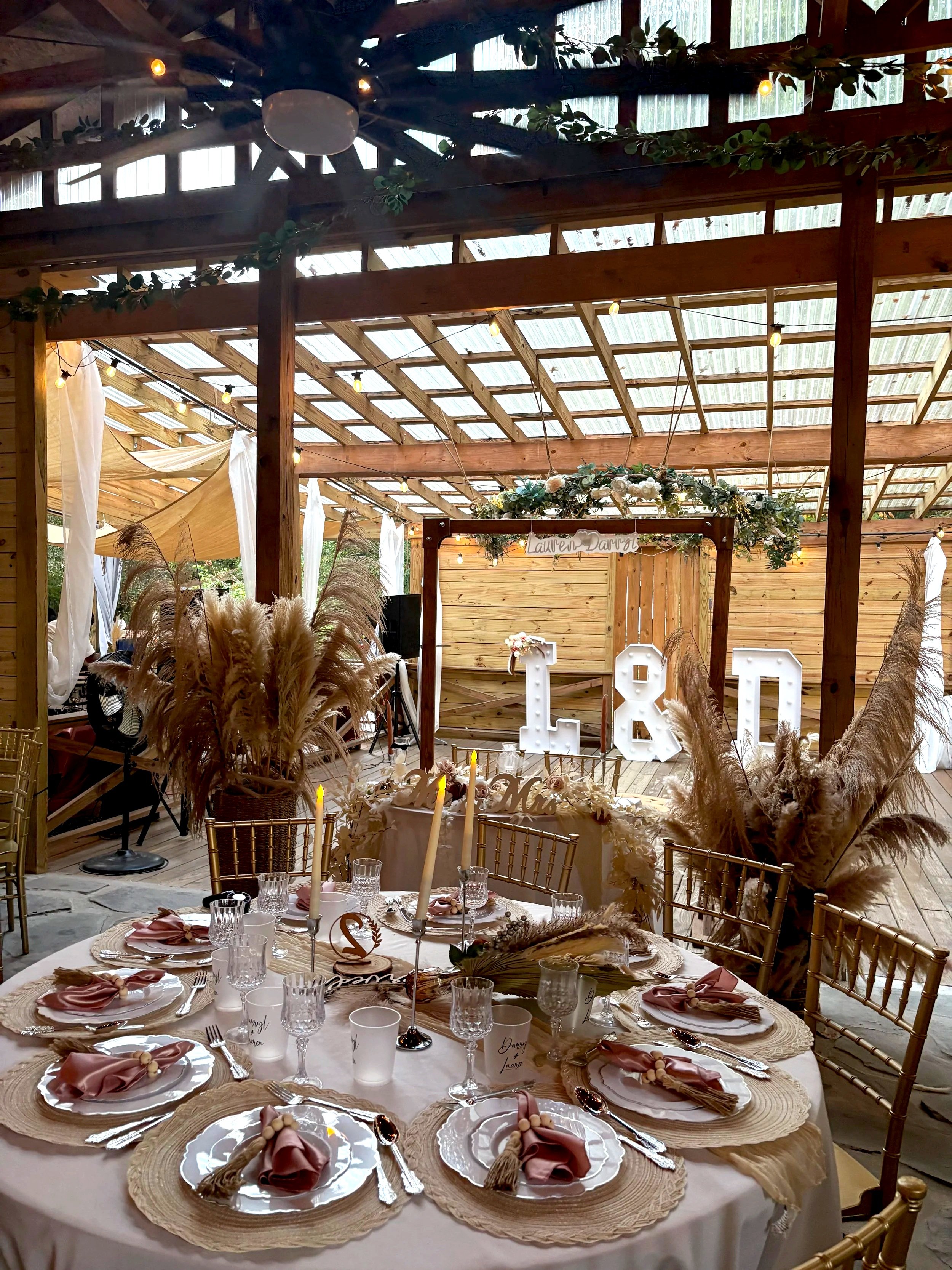 Outdoor wedding scene with a decorated table set for an event, placed on a wooden dance floor.
