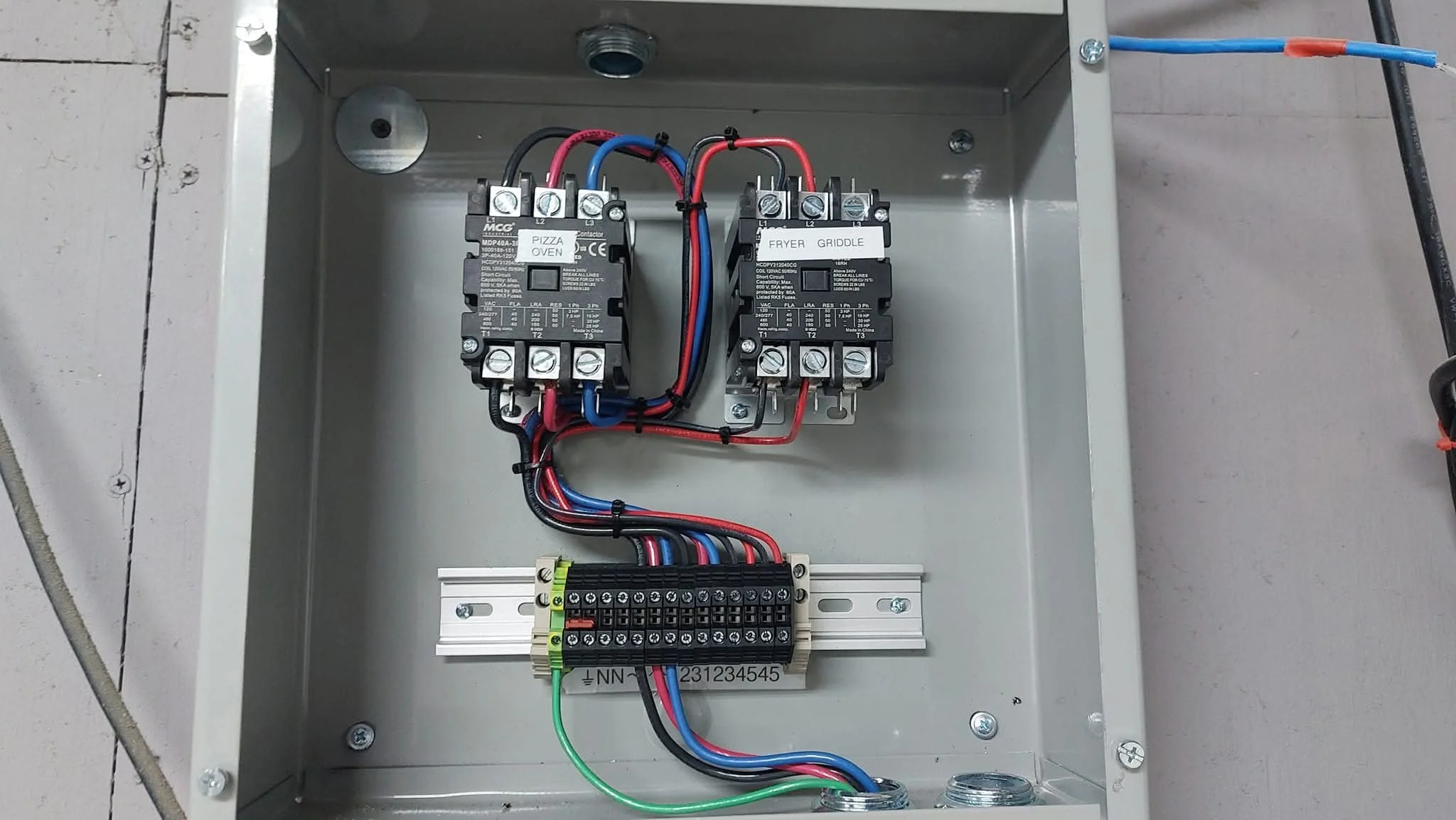 Interior of an electrical control box with wiring, relays labeled 'Pizza Oven' and 'Fryer Griddle', and a terminal block at the bottom.