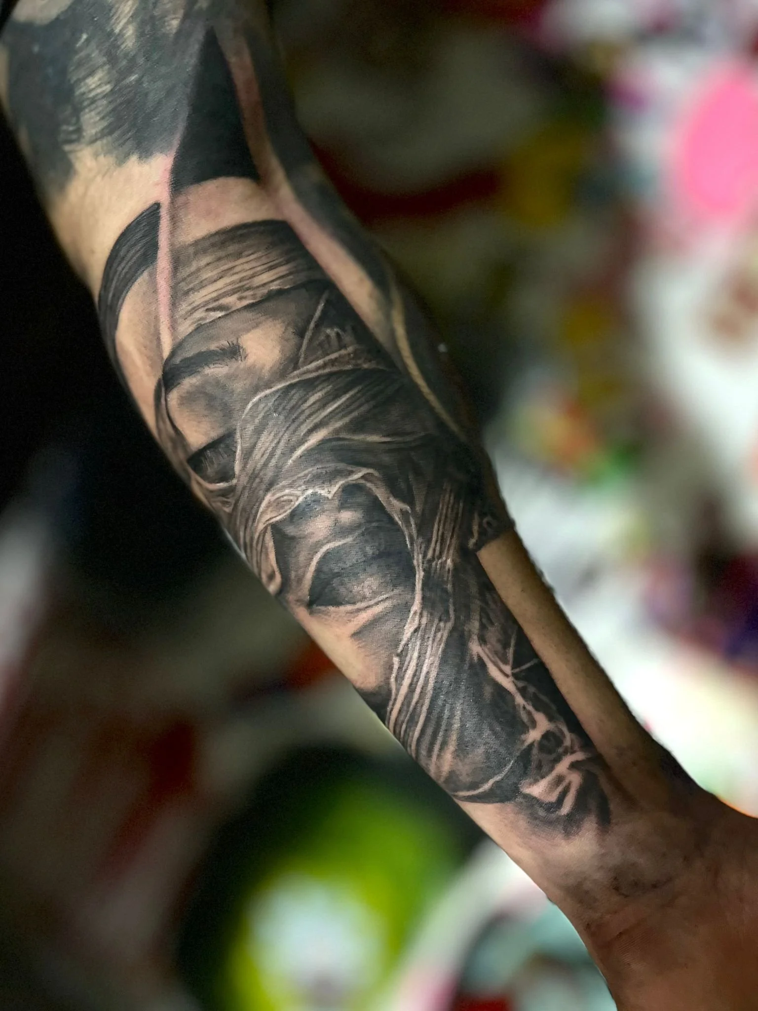 Black and gray realistic tattoo of a woman wearing a hoodie on a person's arm.