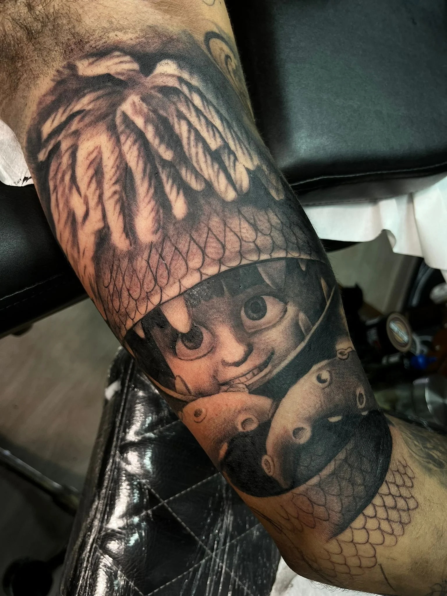 Tattoo of a girl with big eyes and a wide grin, holding a pig, on a person's arm with fish scale pattern tattoos nearby.