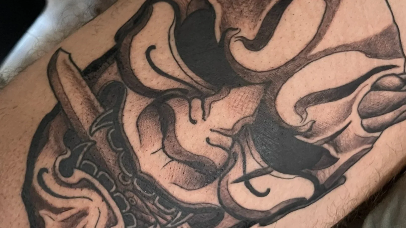 Tattoo of a woman's face with flowing hair, outlined in black ink.