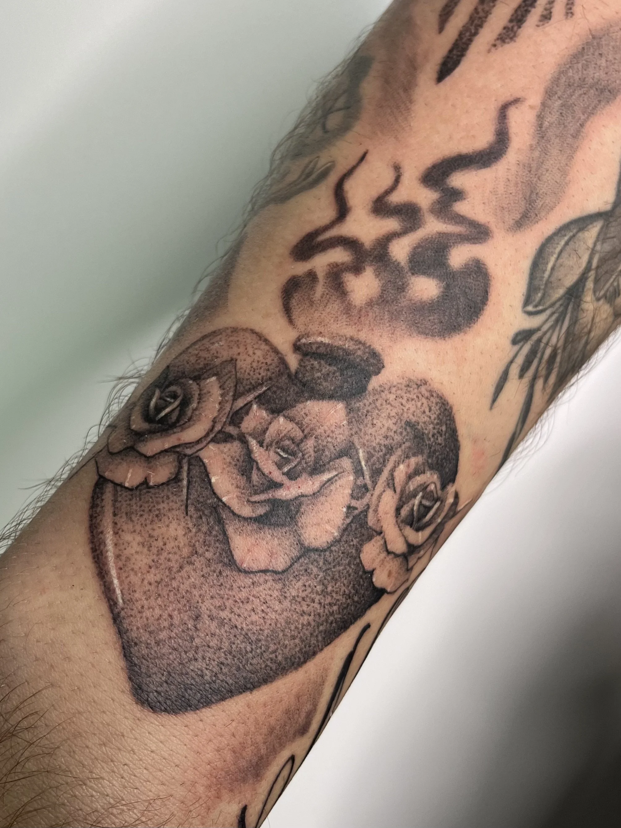 Tattoo of a heart with roses on a person's arm.