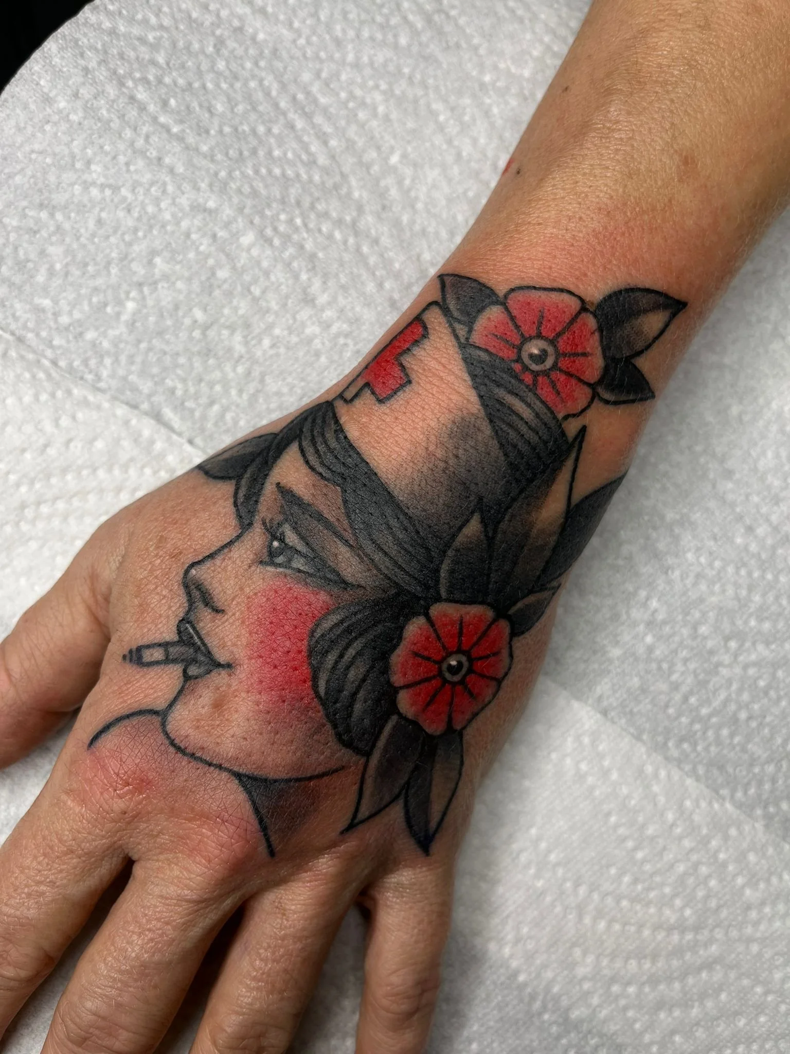 Tattoo of a woman's profile with flowers and leaves on the arm.