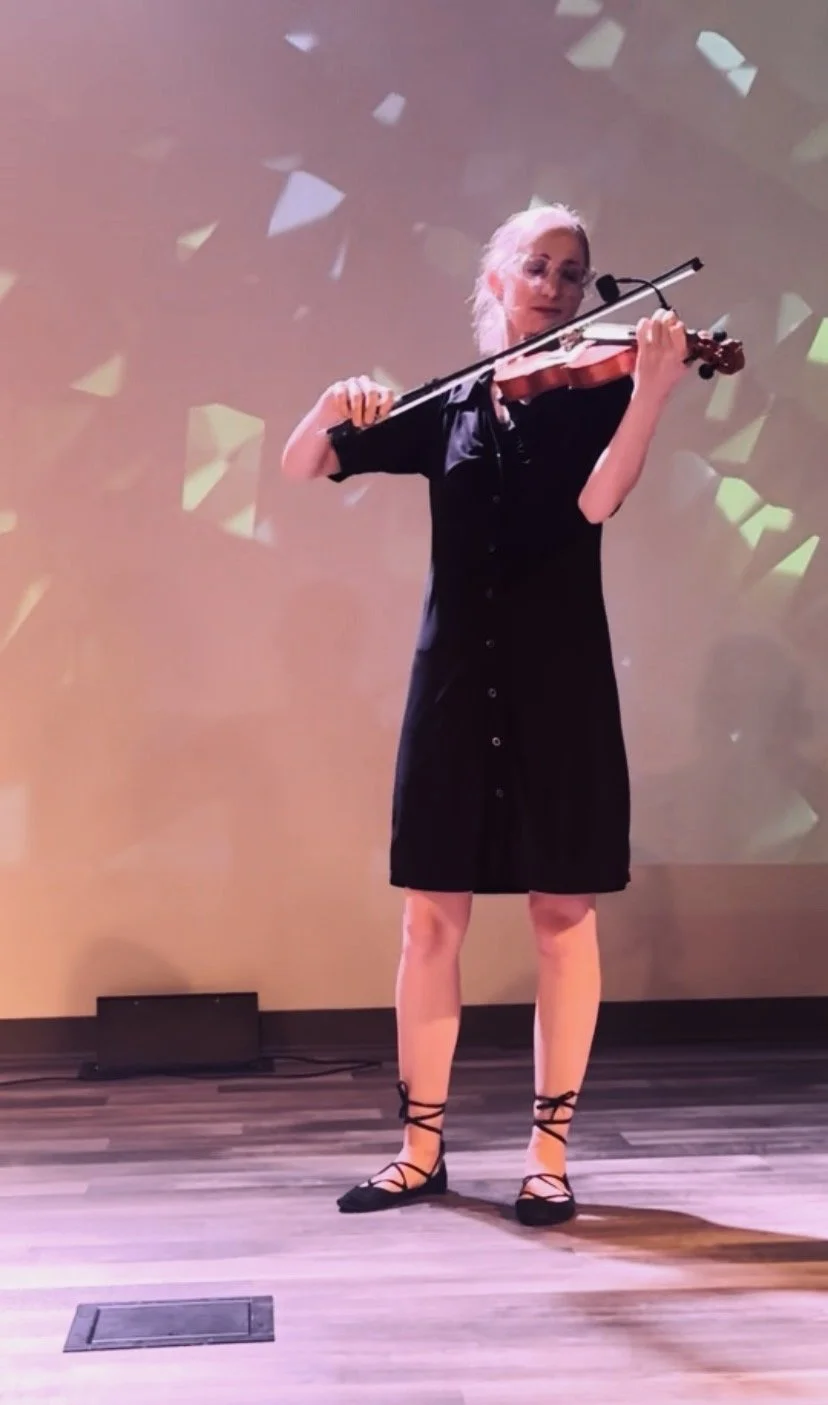 Woman playing the violin on stage with abstract colorful background.