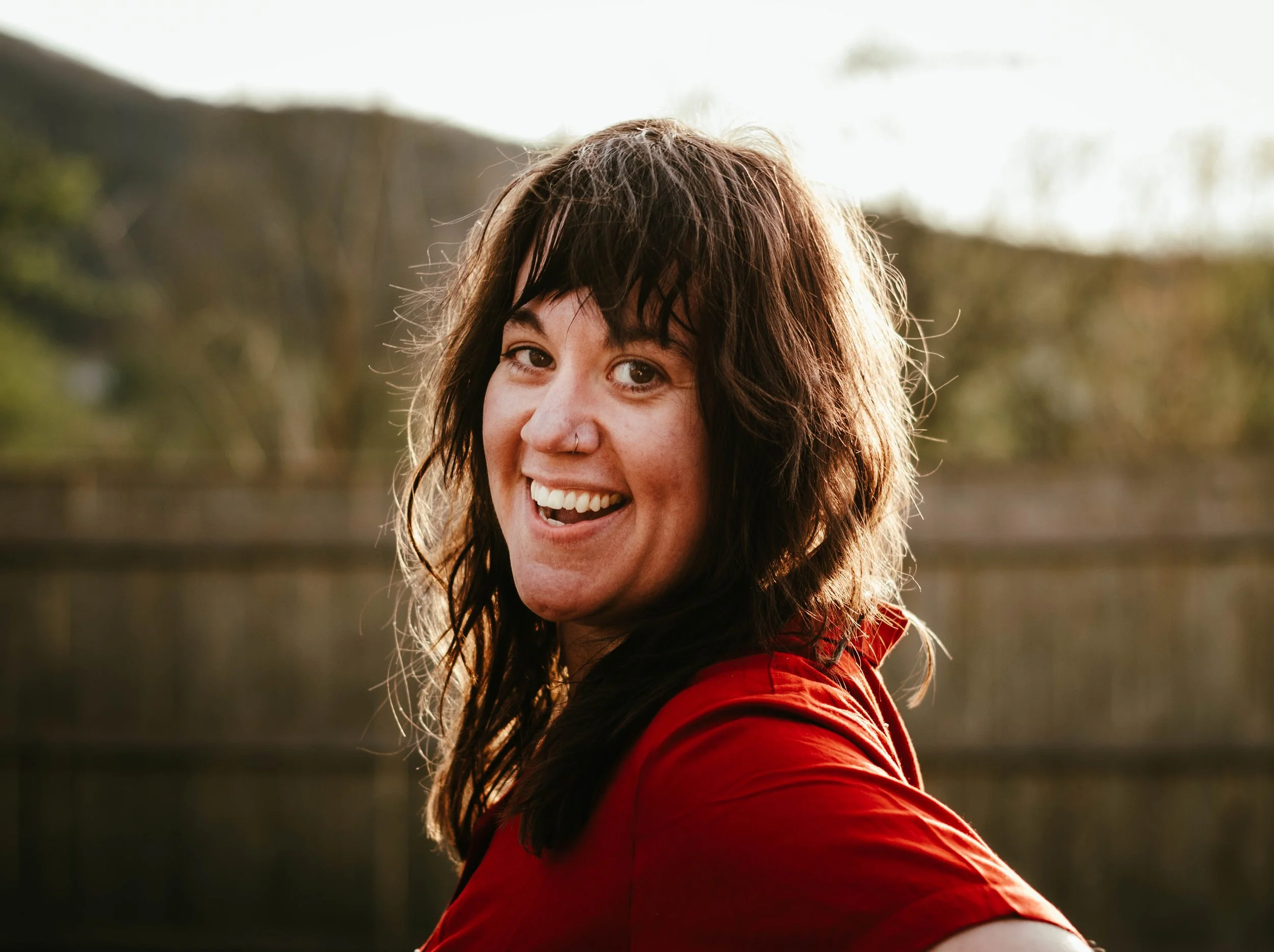 A woman with long brown wavy hair and brown eyes smiling at the camera.