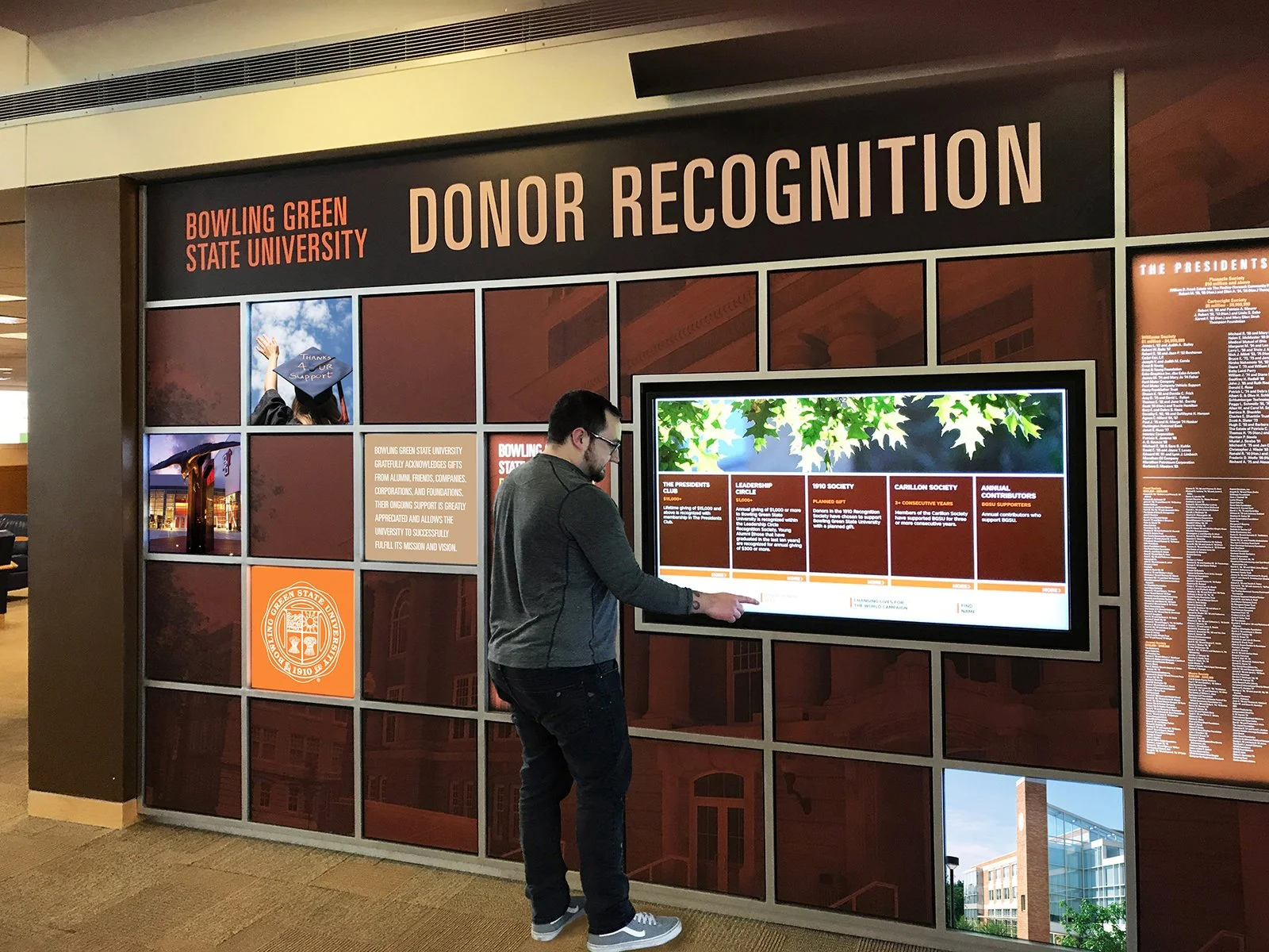 A man looks at a digital display board in a building at Bowling Green State University, recognizing donors with a sign reading 'Donor Recognition'.