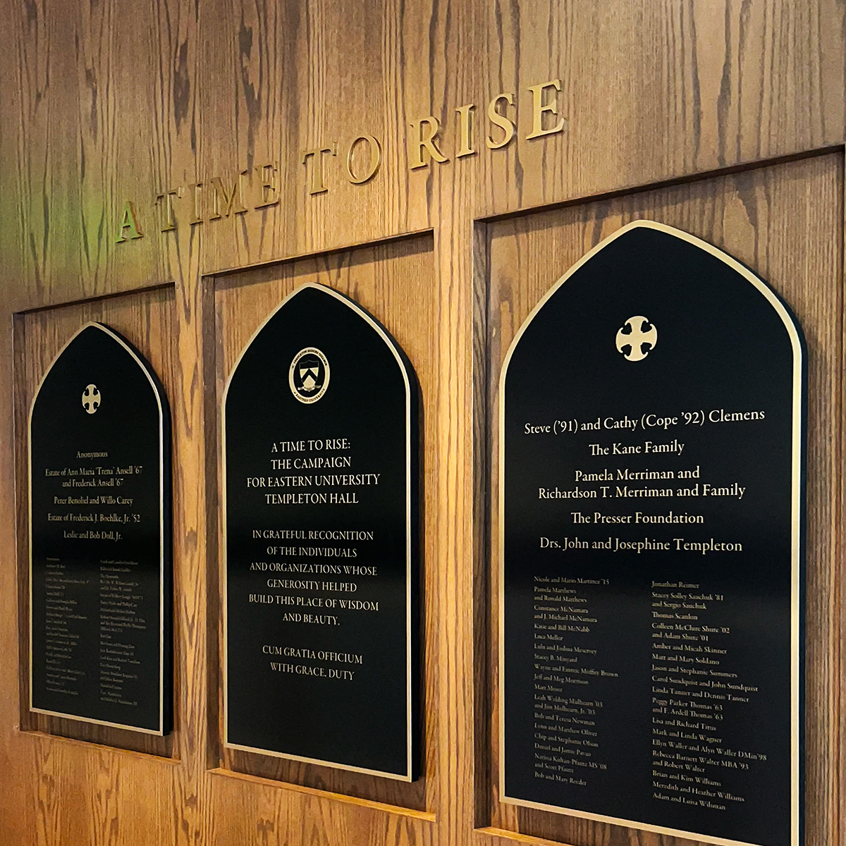 Wooden wall with three black plaques reading "A Time to Rise" and listing names and acknowledgments for Eastern University Templeton Hall campaign.