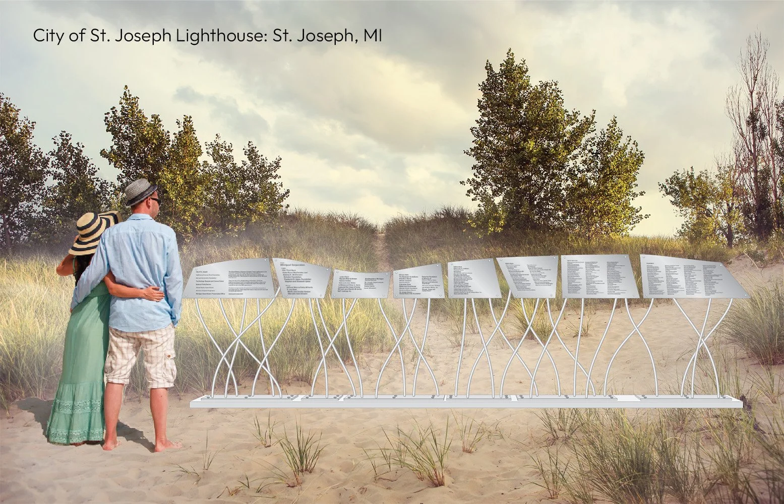 A couple stands on a sandy path at the St. Joseph Lighthouse in St. Joseph, MI, looking at informational plaques mounted on a decorative metal stand against a background of tall grass and trees under a cloudy sky.