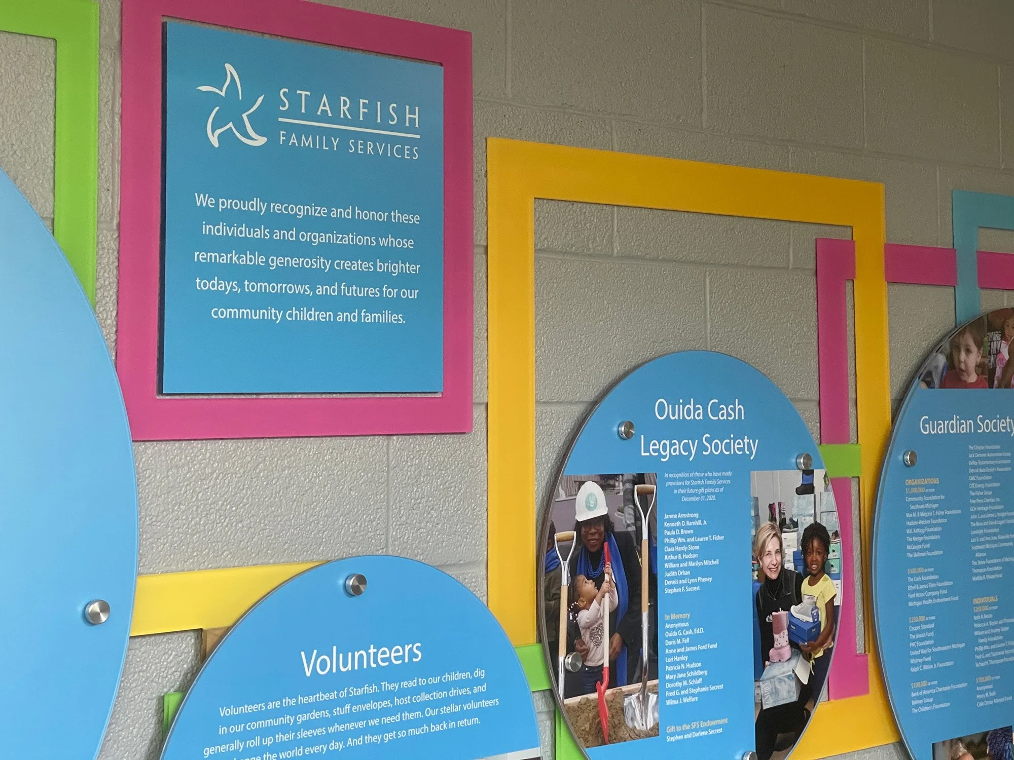 Colorful display of plaques and photos recognizing community organizations and volunteers at Starfish Family Services, featuring a blue plaque about community recognition, with photos of people engaging in service activities.