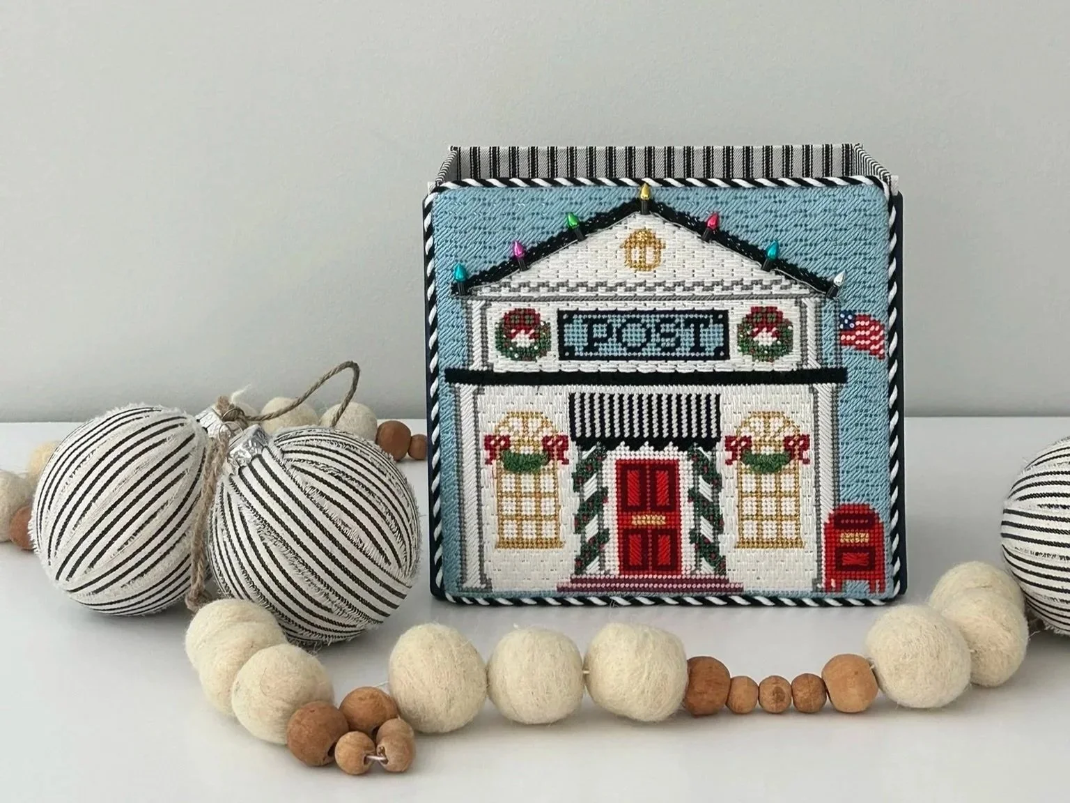 Holiday mailbox decorated for Christmas, surrounded by striped and felt ball ornaments.