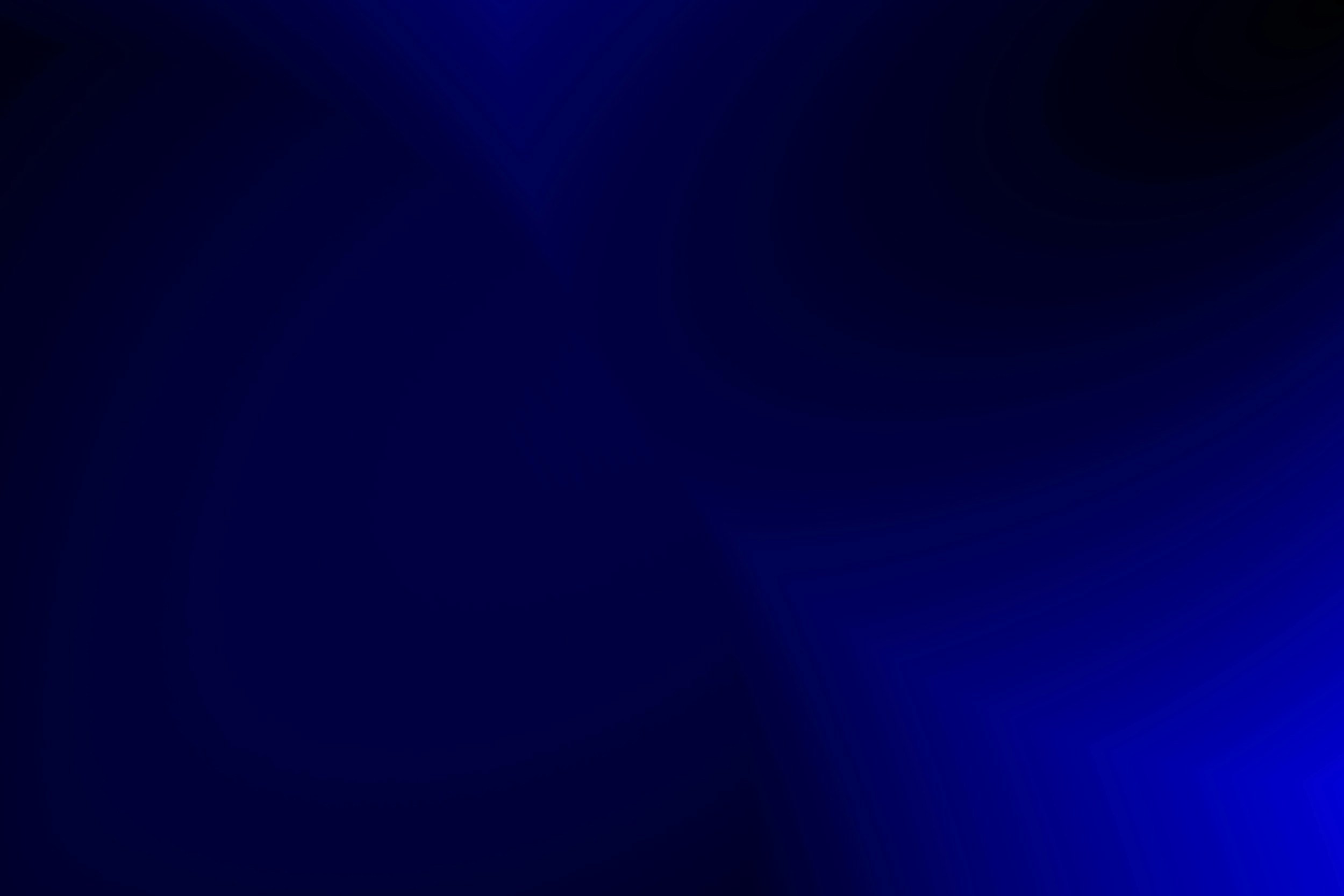 Blurred blue and black abstract background with waves of color.