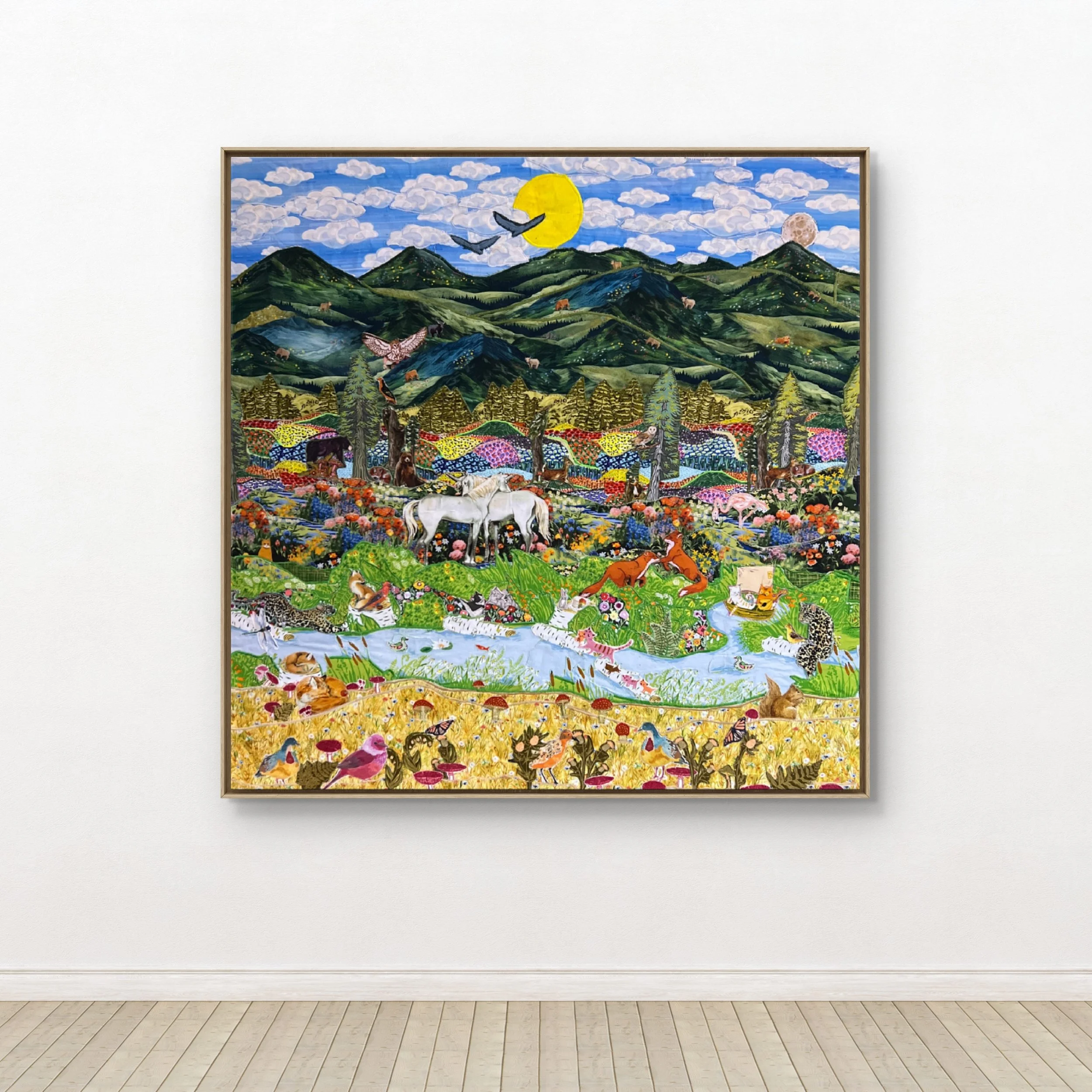Colorful landscape textile collage with mountains, trees, animals, and a bright sun or moon in the sky.