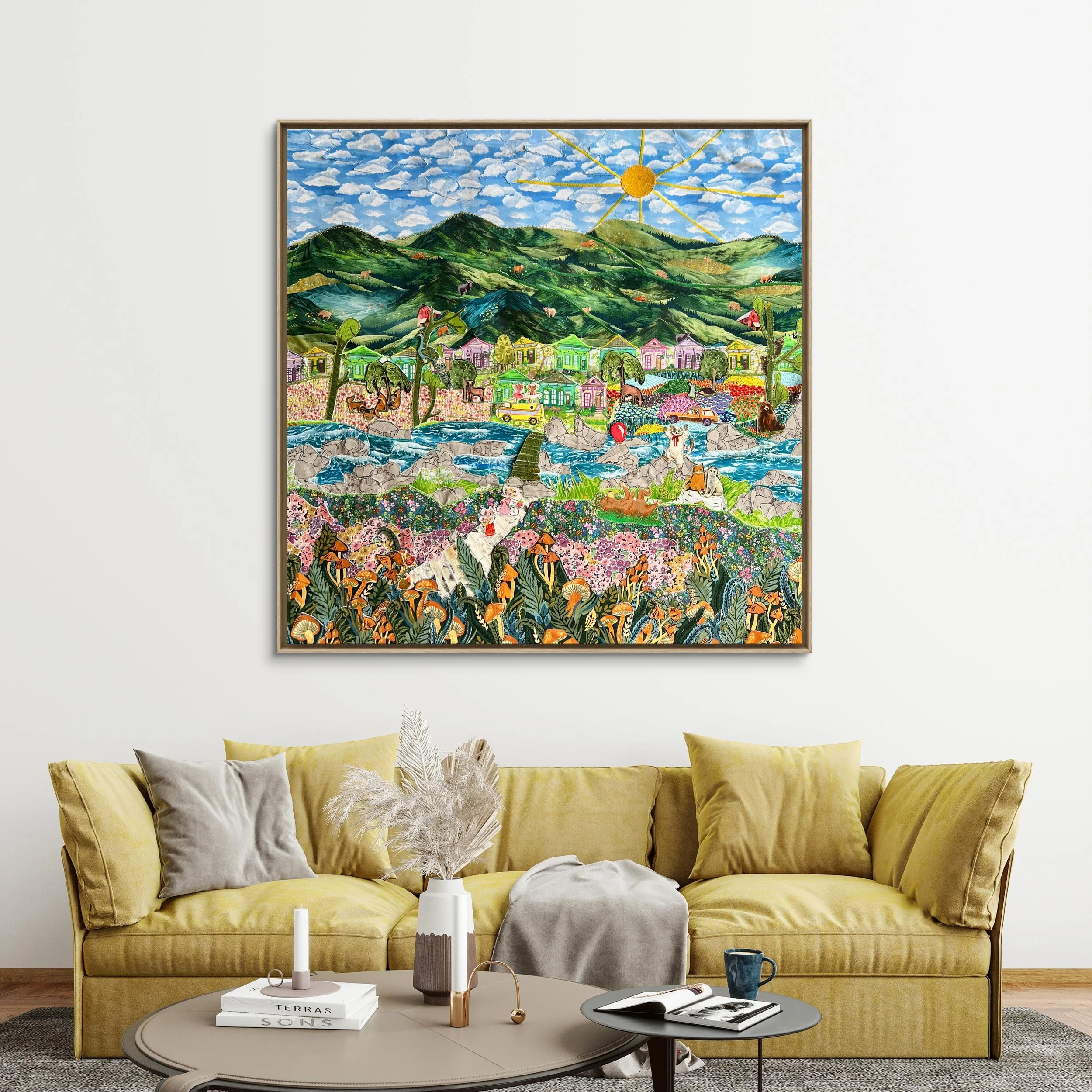 Colorful fabric collage featuring a landscape with green mountains, a blue sky with clouds, a yellow sun with rays, a river with rocks, trees, houses, and animals, hanging on a white wall above a yellow sofa.