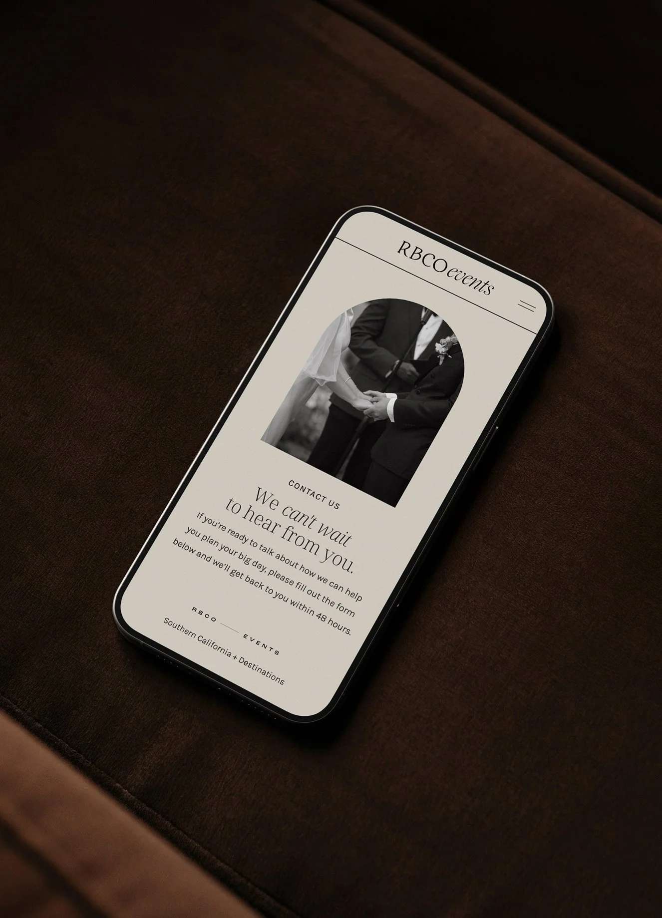 A smartphone displaying an event website with a black and white photo of a wedding couple holding hands, and text about upcoming events in Southern California and destination events.