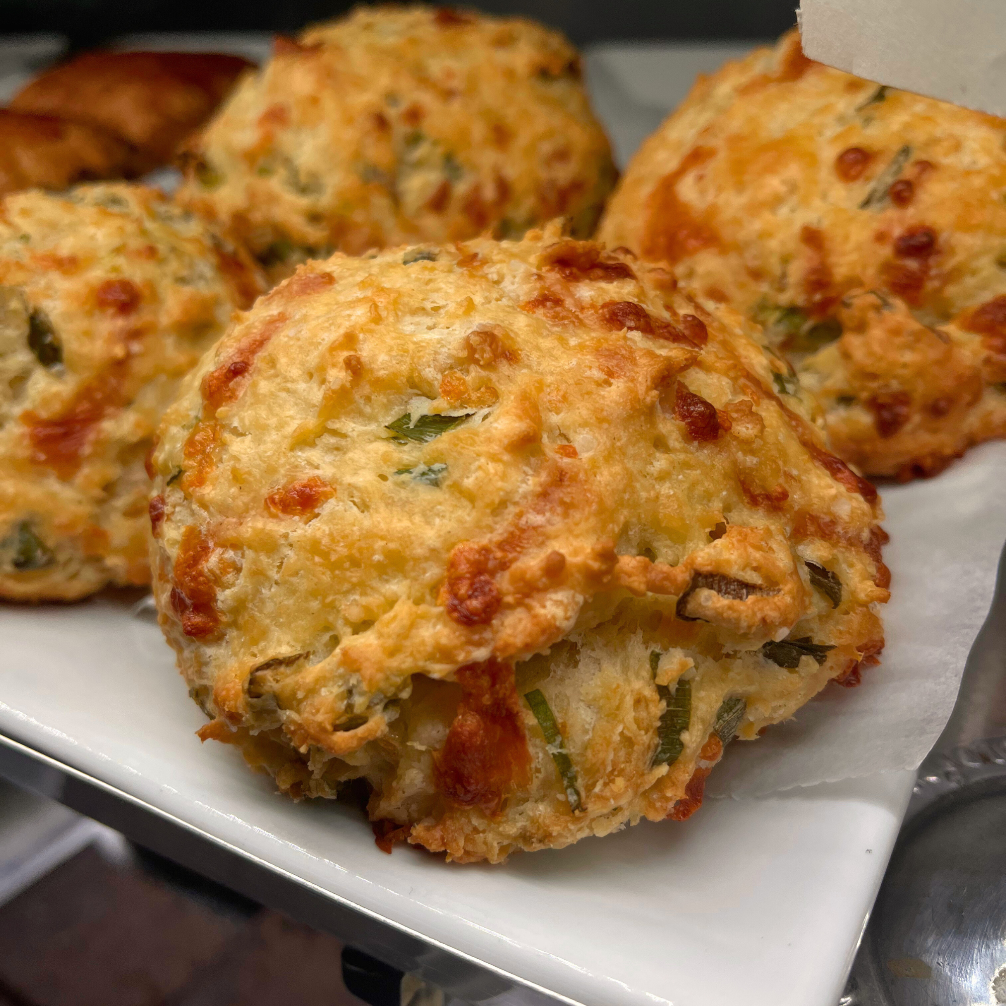 Close-up of cheesy baked crab cakes on a white plate.