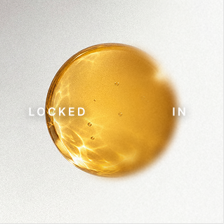 A gold-colored, rounded capsule with light reflections on it, with the words 'LOCKED' on the left and 'IN' on the right.