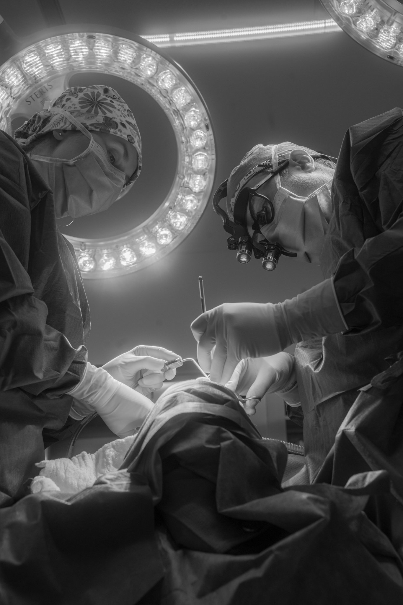 Surgeons performing an operation in the operating room under bright surgical lights.