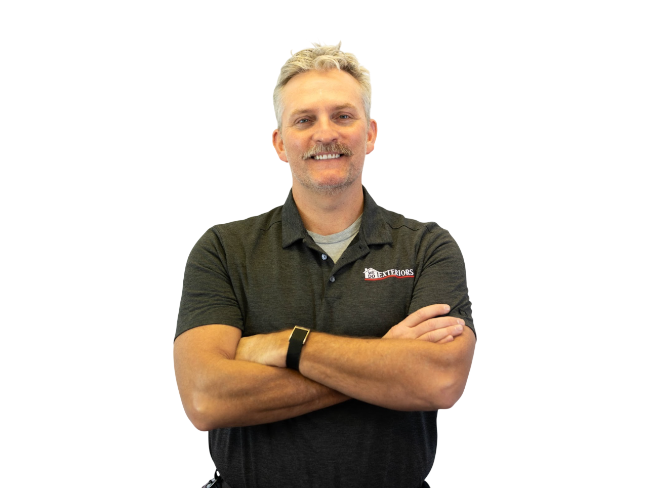 Middle aged man with short grey hair and a striking mustache, smiling warmly at the camera with his arms crossed, wearing a branded grey polo style shirt, against a white background.