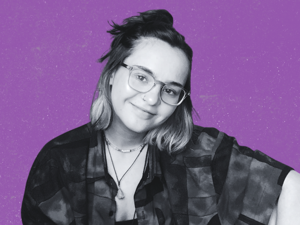 Health Content Writer with glasses and short hair, smiling, against a purple background.