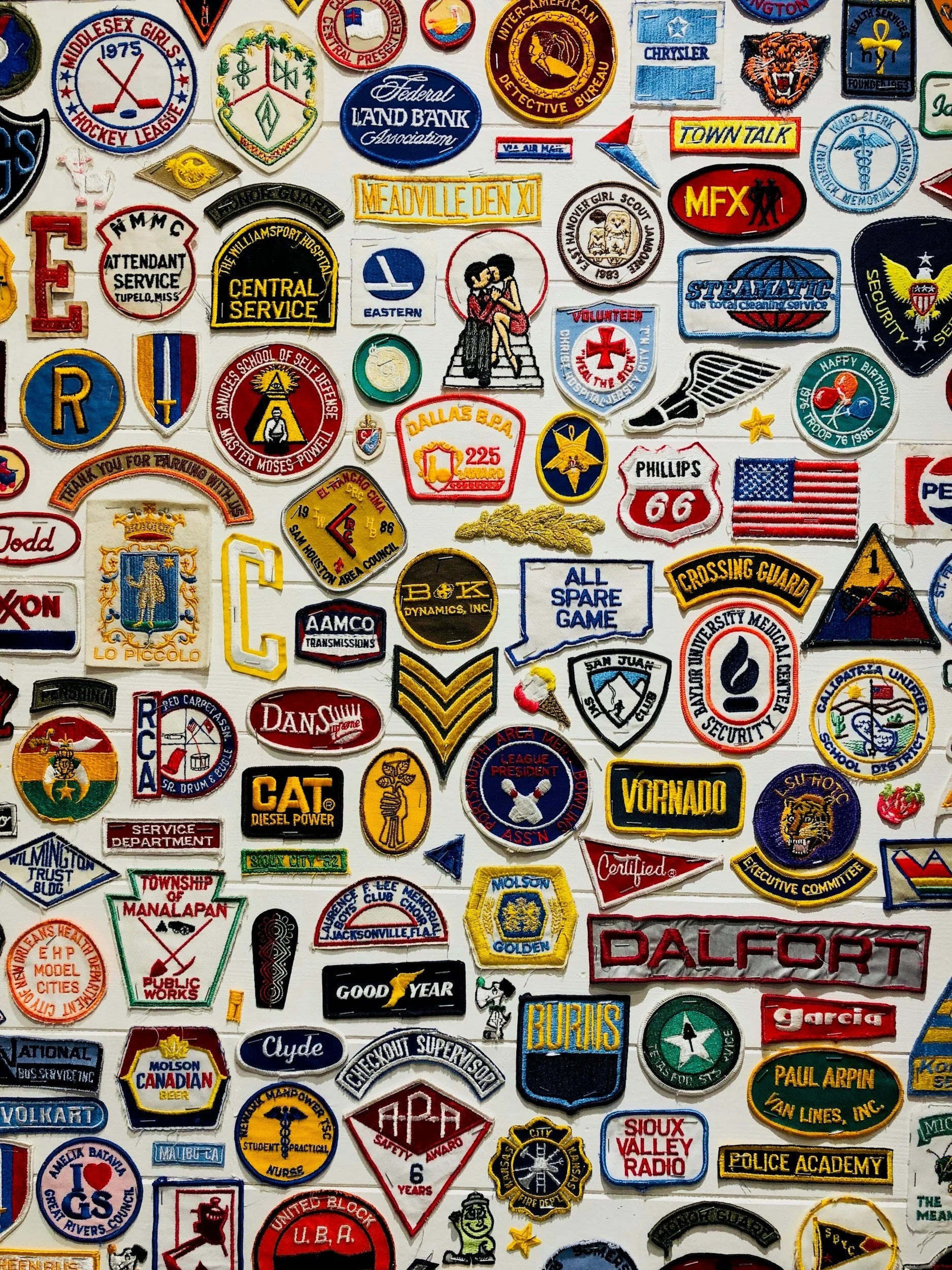 A collection of various embroidered patches representing organizations, clubs, companies, and mascot logos, arranged closely together.