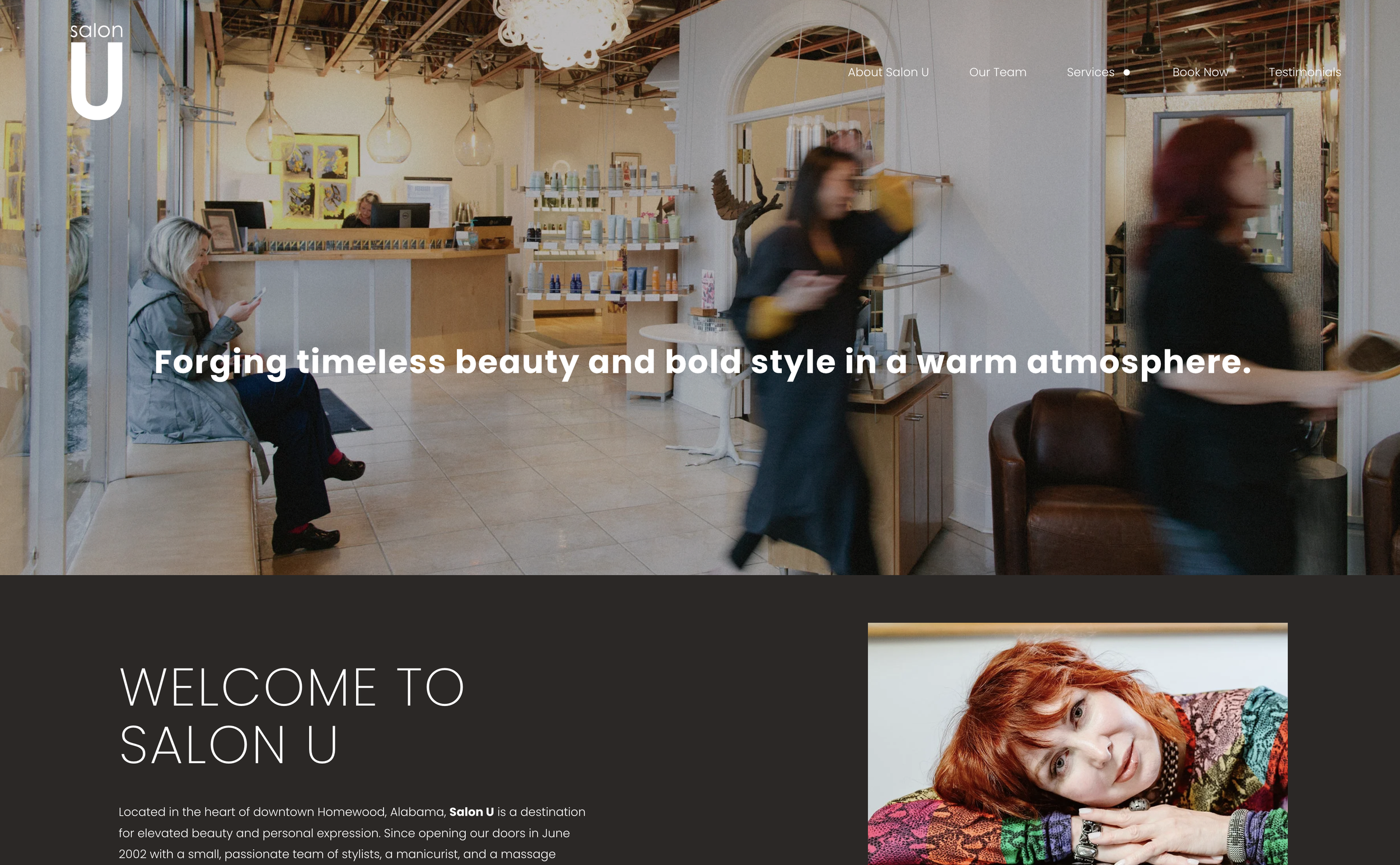 Interior of Salon U with woman sitting on bench looking at phone, blurred woman walking past, receptionist at the desk, and walls decorated with colorful art, modern lighting fixtures, and a white chandelier.