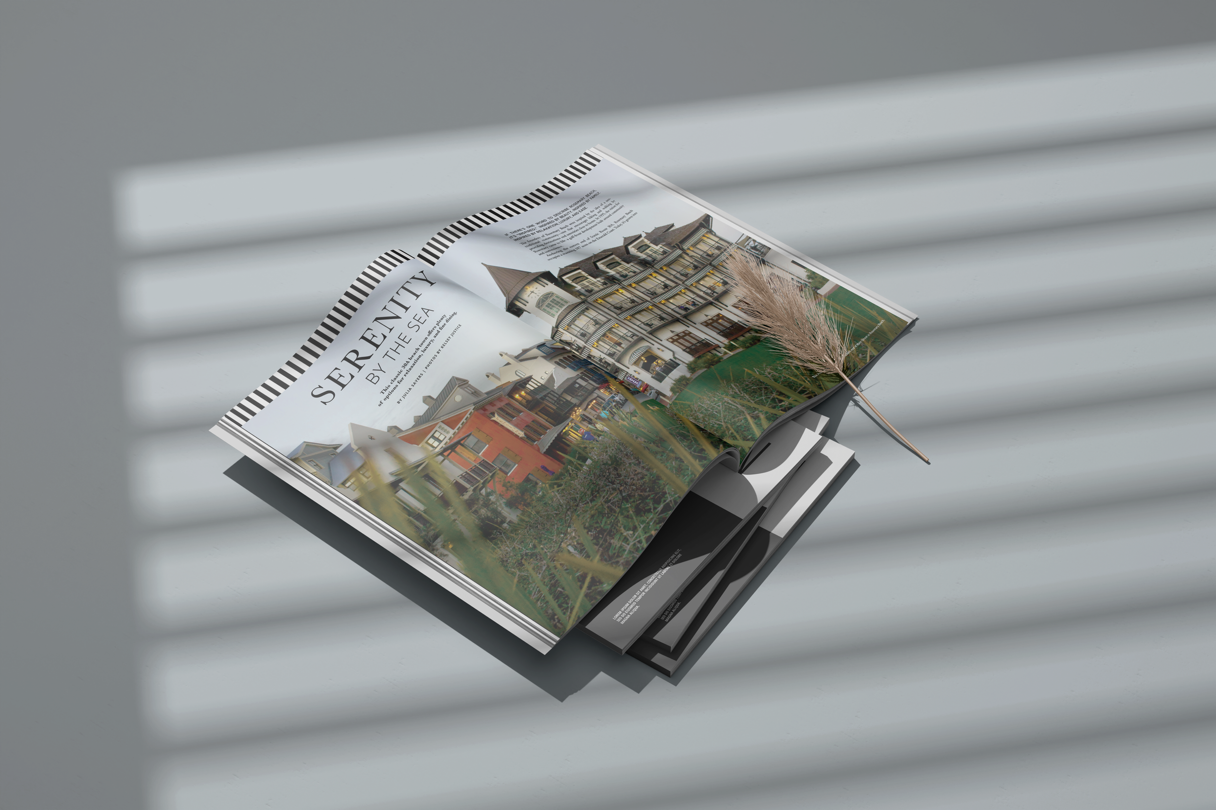 Open magazine featuring a colorful row of houses under the heading 'Serenity by the Sea', laying on a gray surface with striped shadows.
