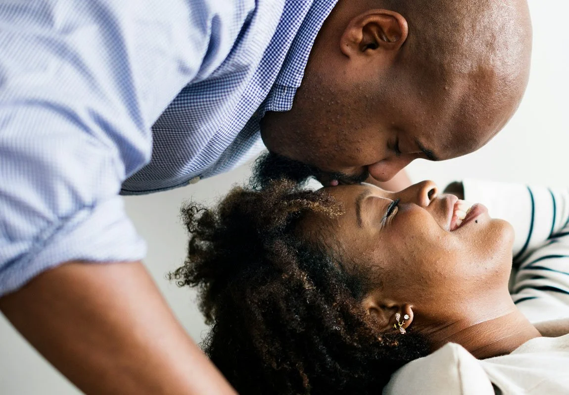 man kissing his wife on the forehead