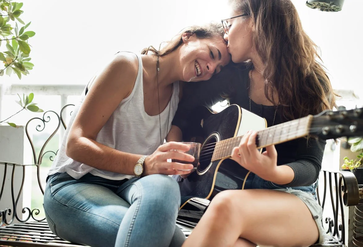 lesbian couple playing music together and smiling