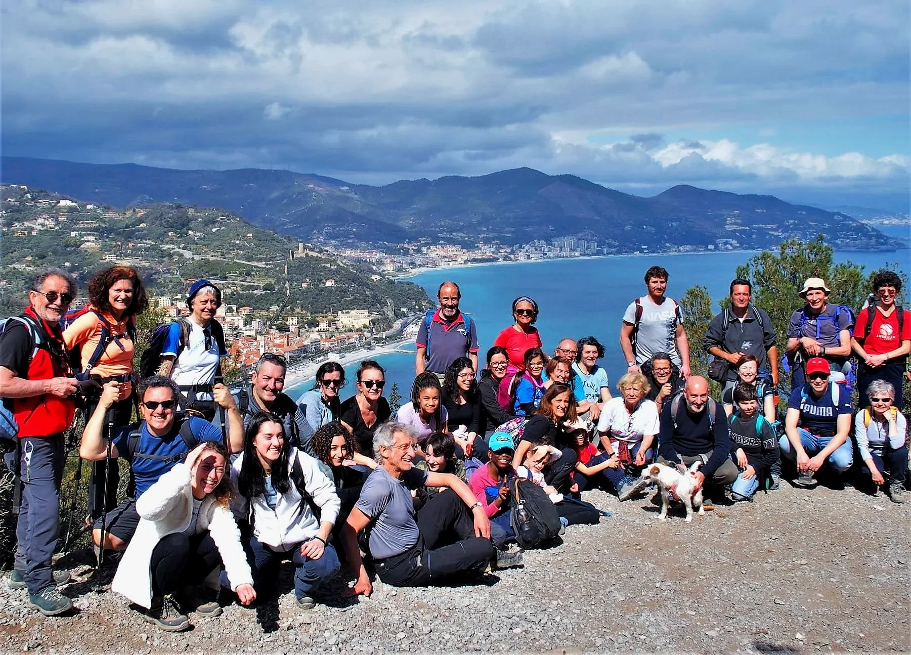 Un gruppo di persone in escursione sulle colline con vista su una città costiera, la spiaggia e il mare