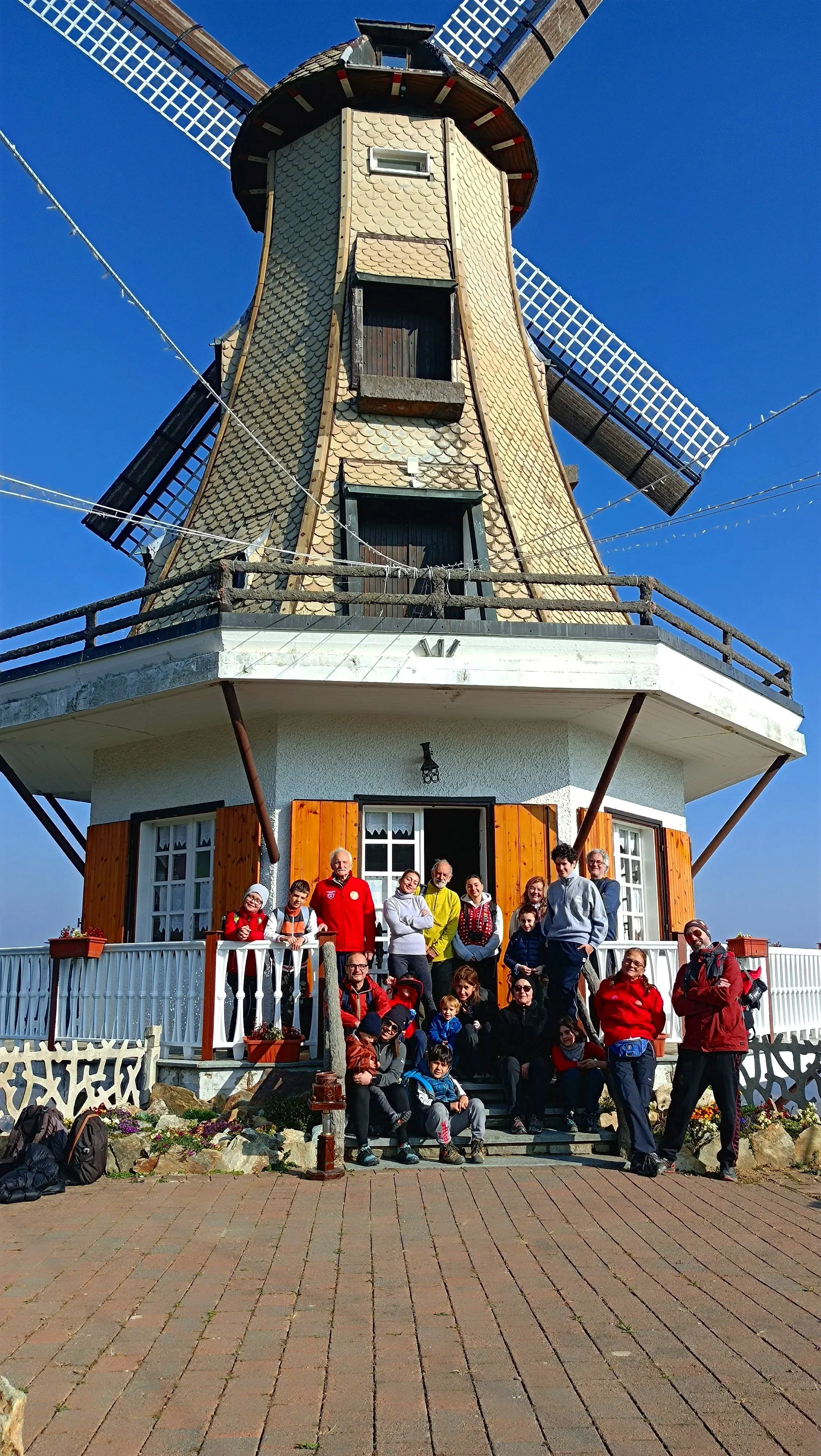 Gruppo di persone davanti a un mulino a vento.