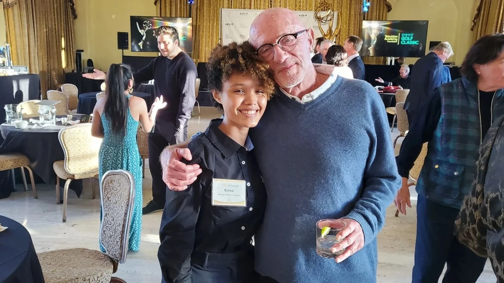Eurice and Jonathan Banks smiling at the Television Academy Foundation Fundraiser, with tables, chairs, and a TV screen in the background.