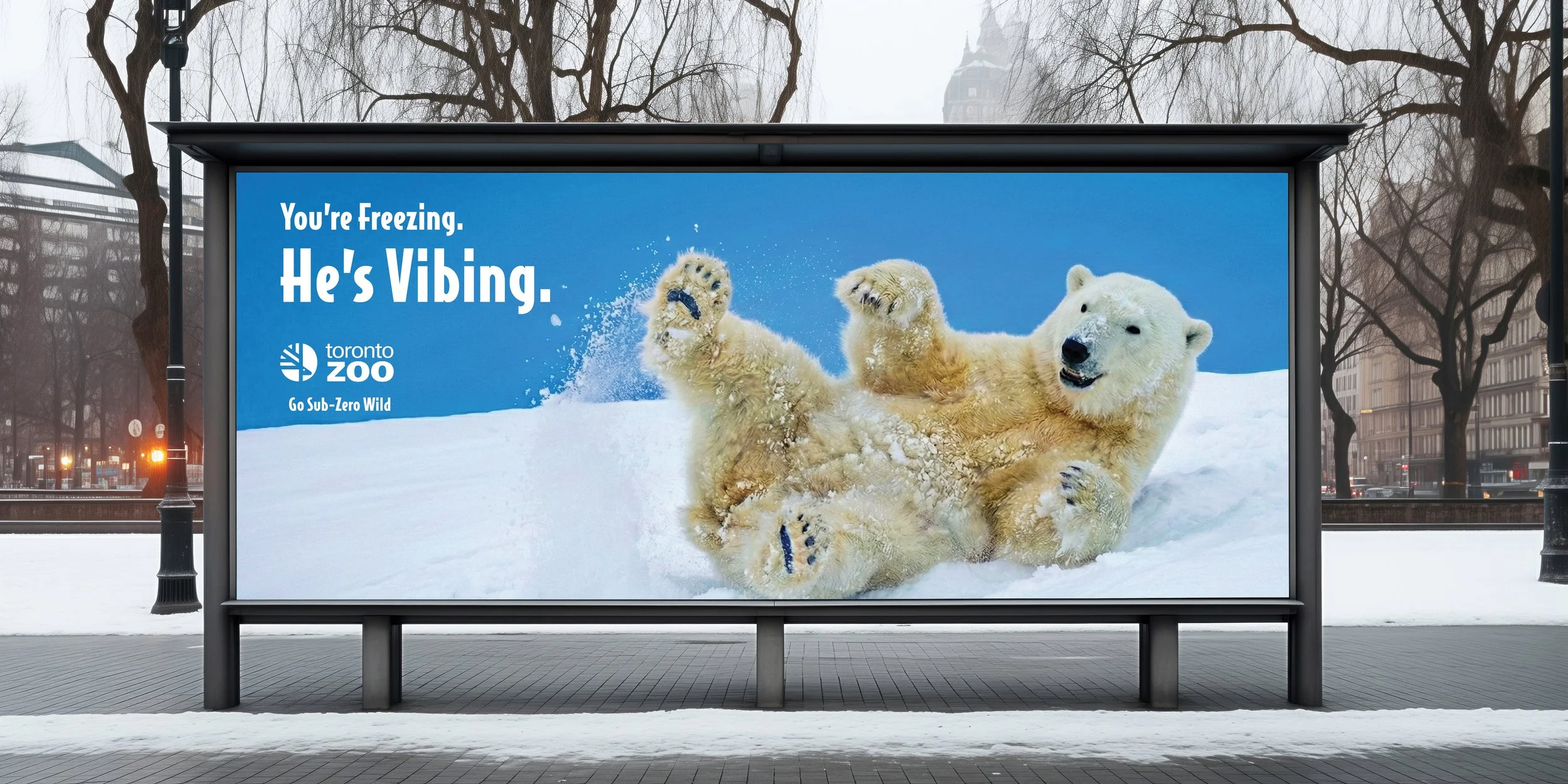 Billboard advertisement for Toronto Zoo featuring a polar bear cub playing in the snow, with the text 'You're Freezing. He's Vibing.' and the zoo's logo.