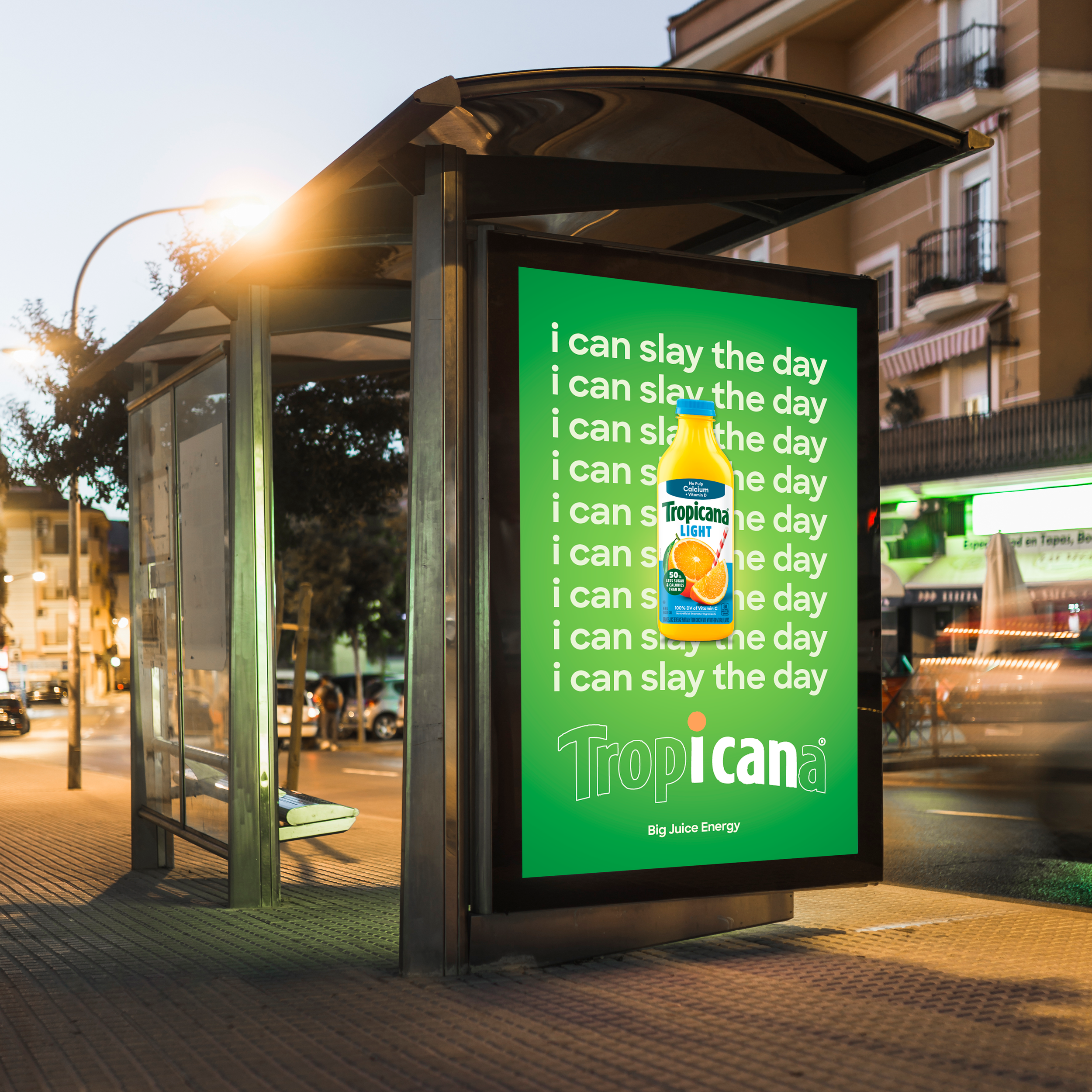 Bus stop shelter with an advertisement featuring Tropicana Light orange juice and the slogan 'I can slay the day' repeatedly in white text on a green background.