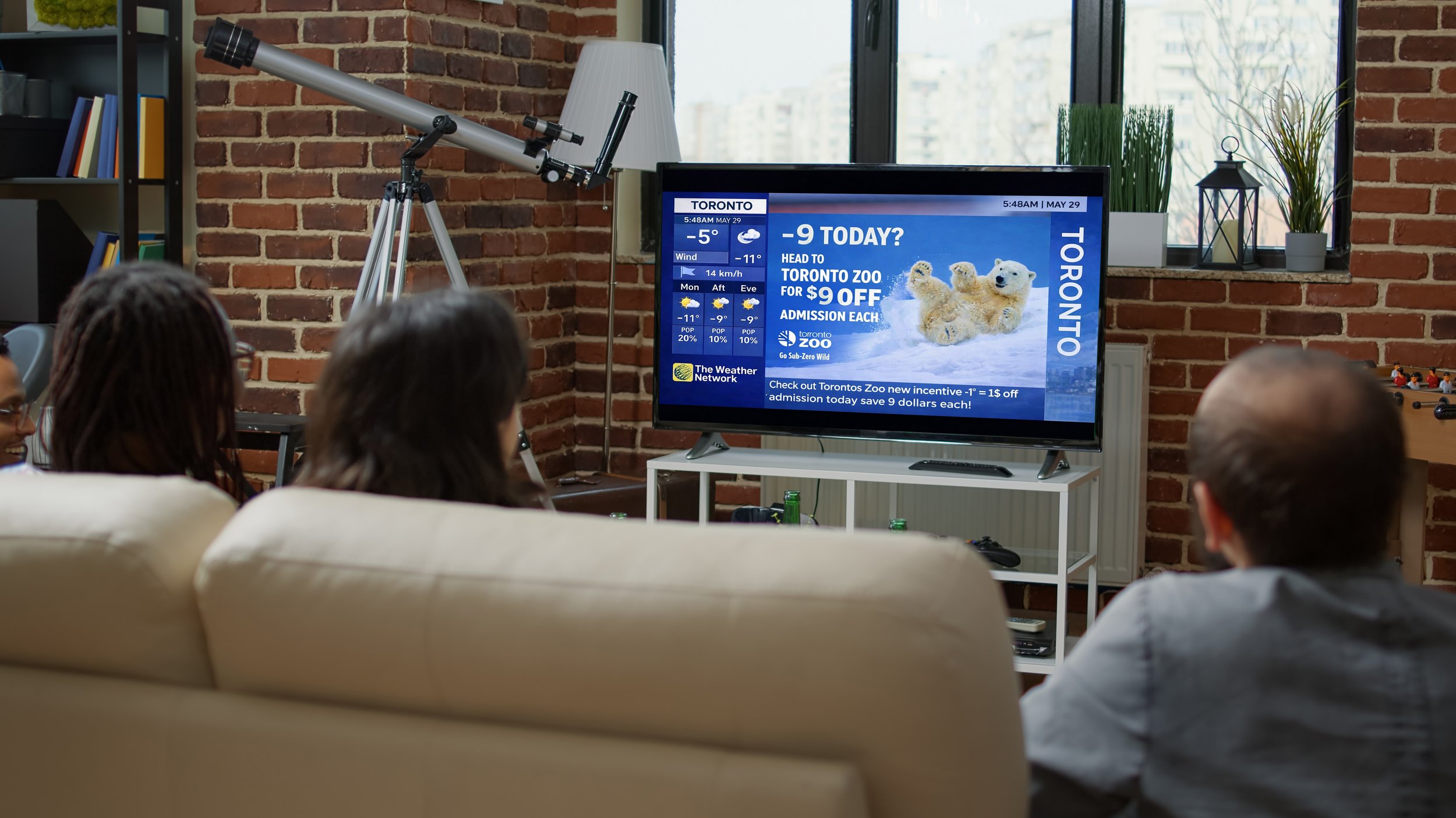 People watching TV displaying a weather forecast and advertisement for Toronto Zoo with a promotion for discounted admission.