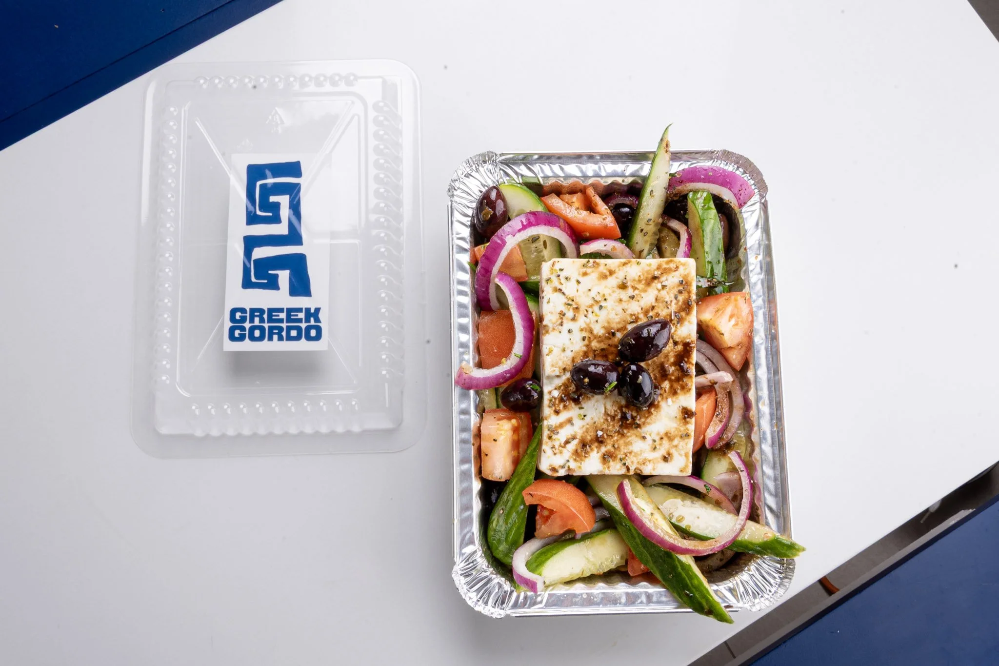 Toronto Best Greek salad with feta cheese, cucumbers, tomatoes, red onions, black olives, and herbs.