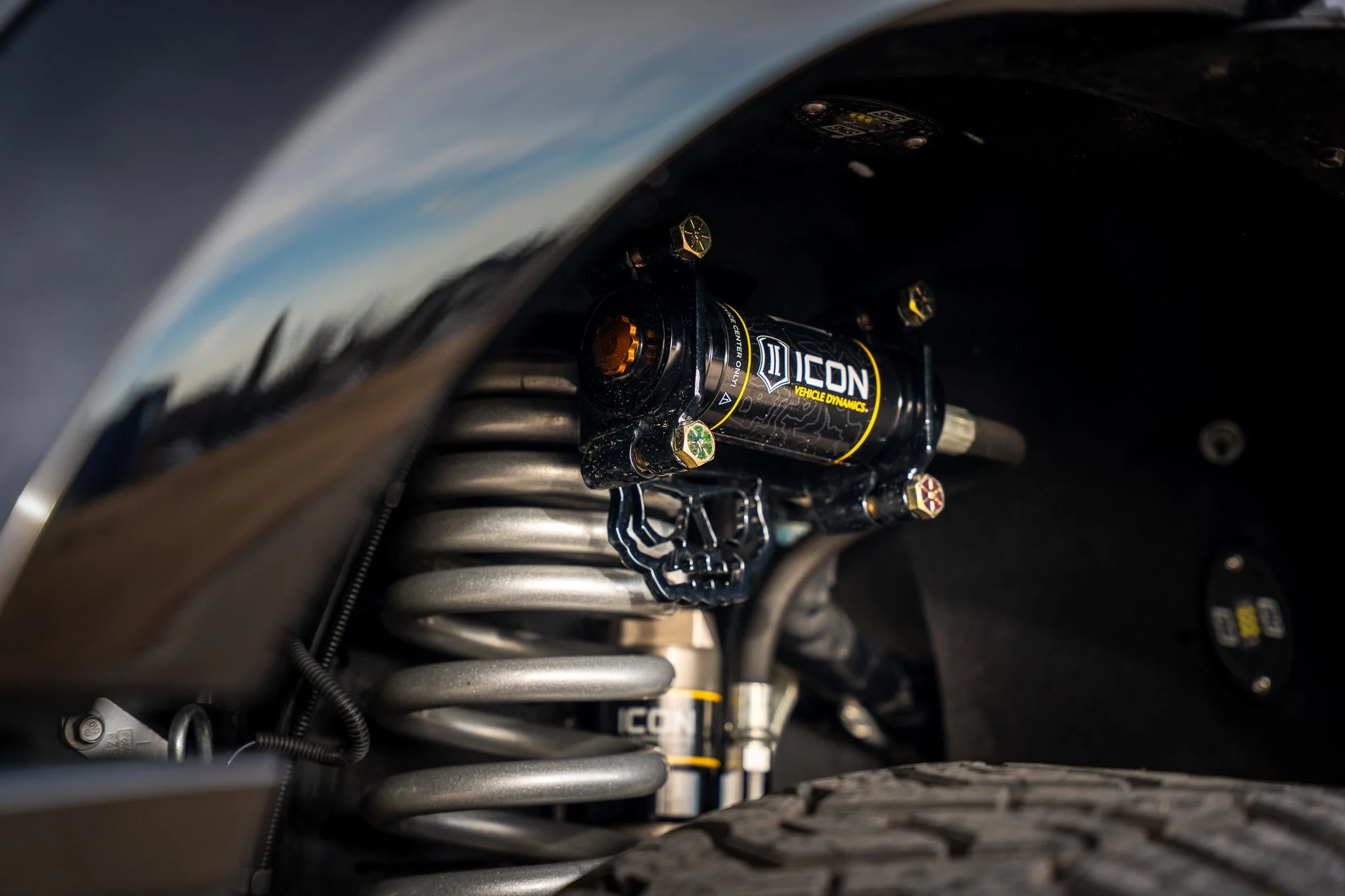 Close-up of a vehicle suspension system with ICON Vehicle Dynamics shock absorber and coil spring.