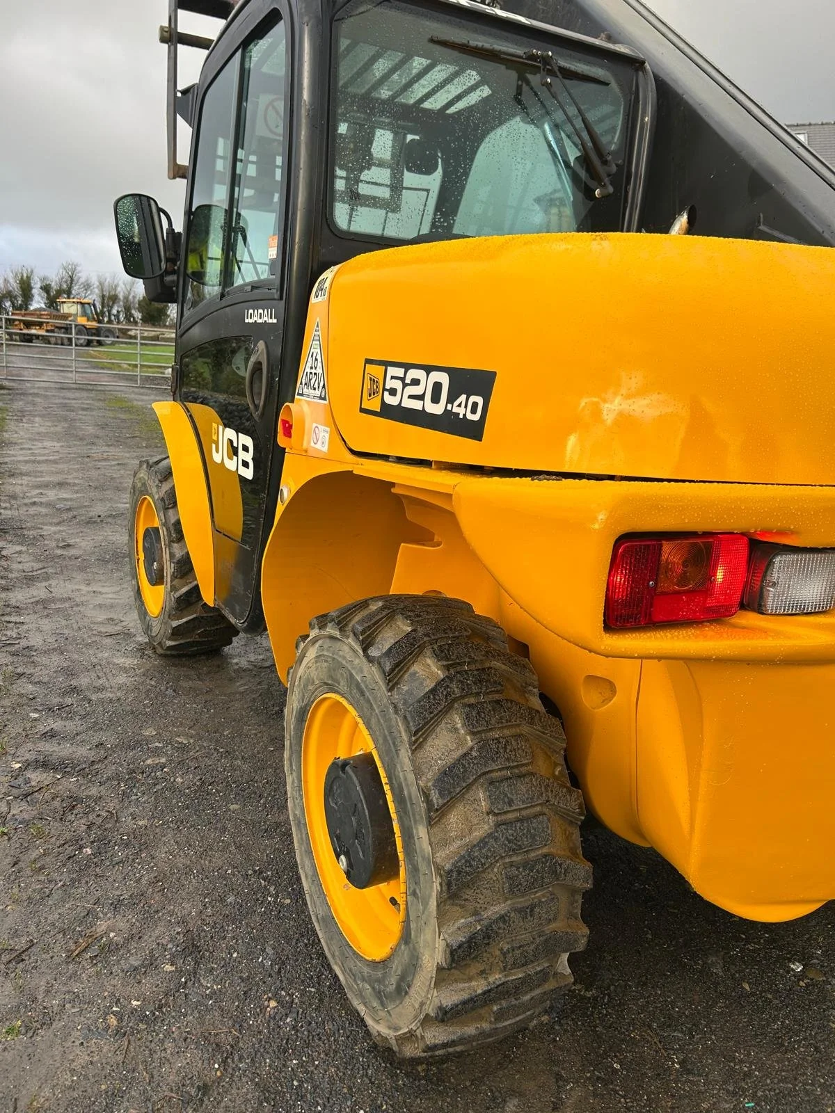Close-up of a yellow and black JCB 520-40 telehandler on a muddy construction site.
