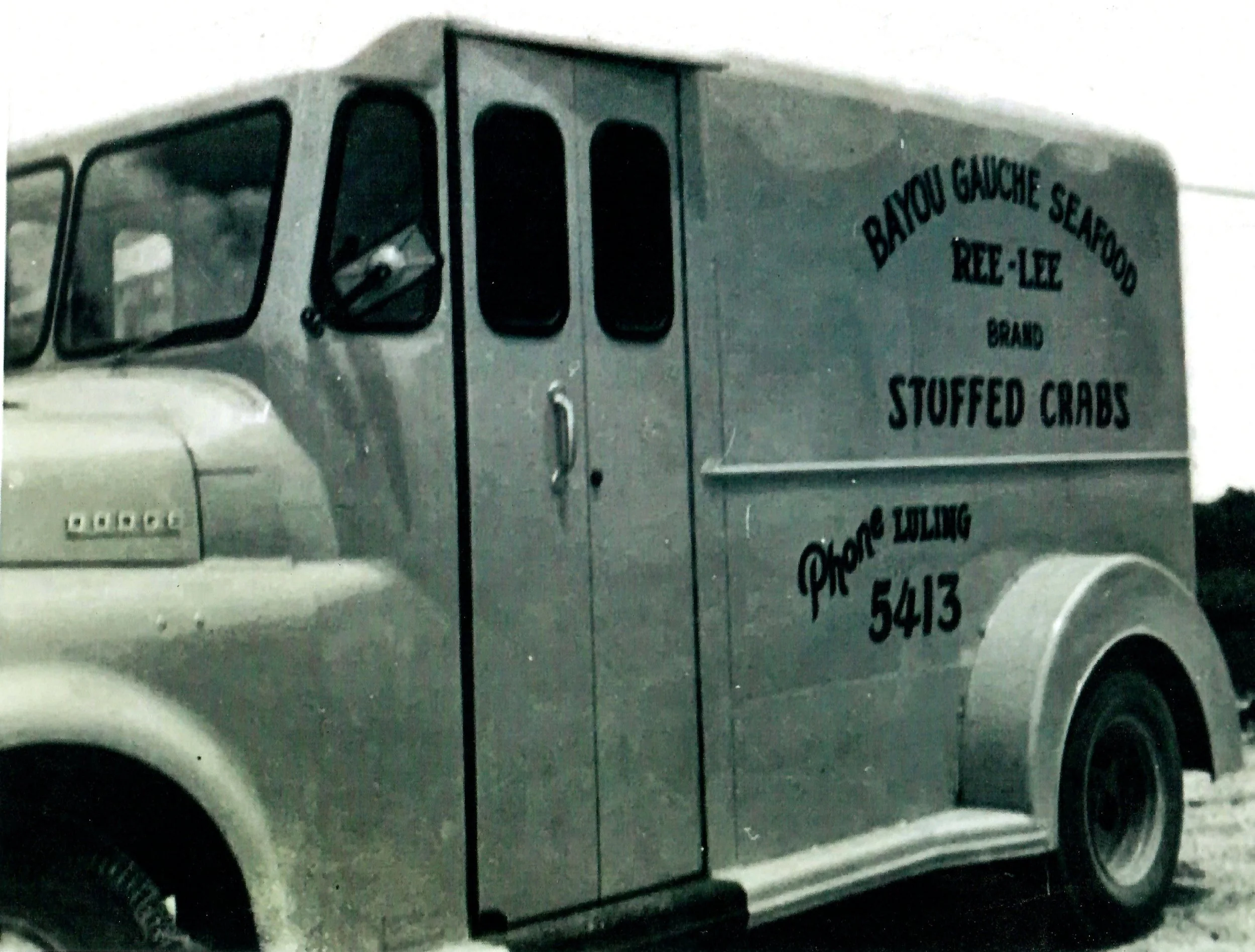 A large truck labeled 'Bayou Gauche Seafood Ree-Lee Stuffed Crabs' with a silver cab, parked on the road.