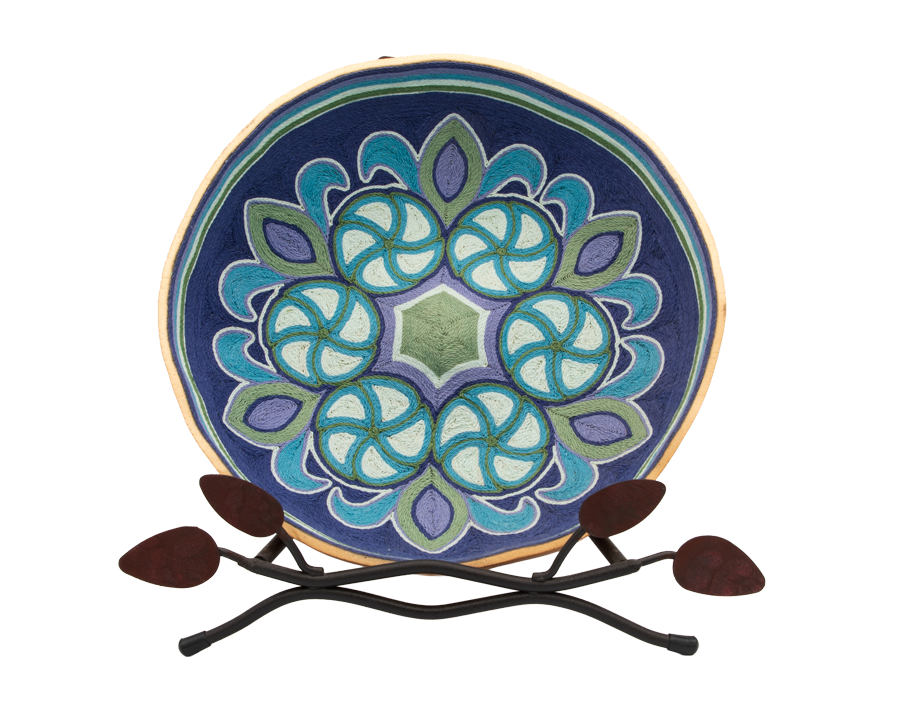 Decorative ceramic plate with geometric blue and green pattern on a metal stand.