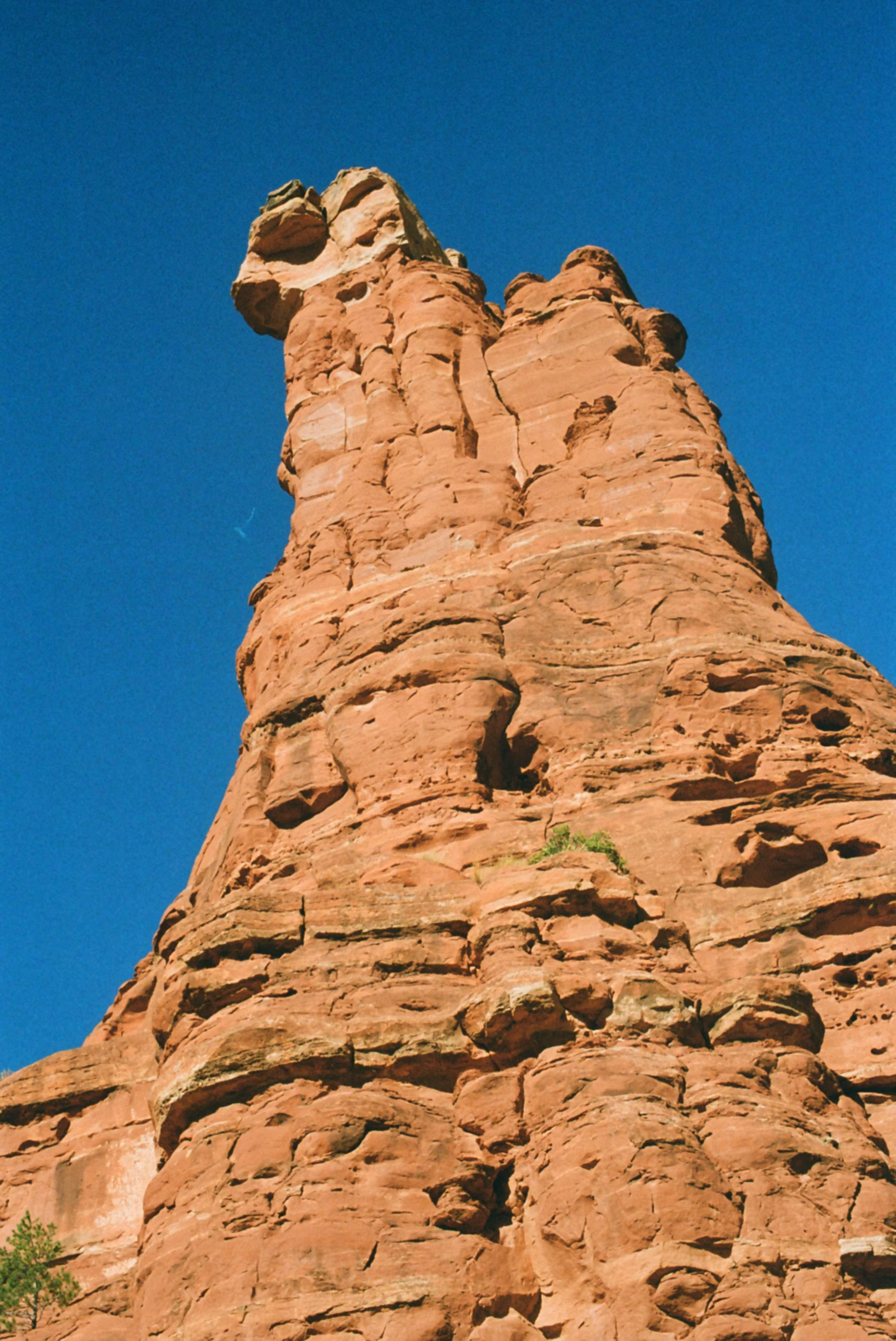 Tall red rock formation against a clear blue sky.