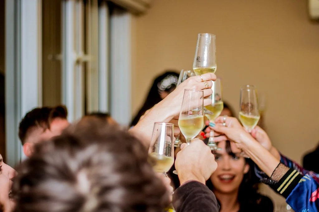 Pessoas brindando com taças de espumante em celebração.
